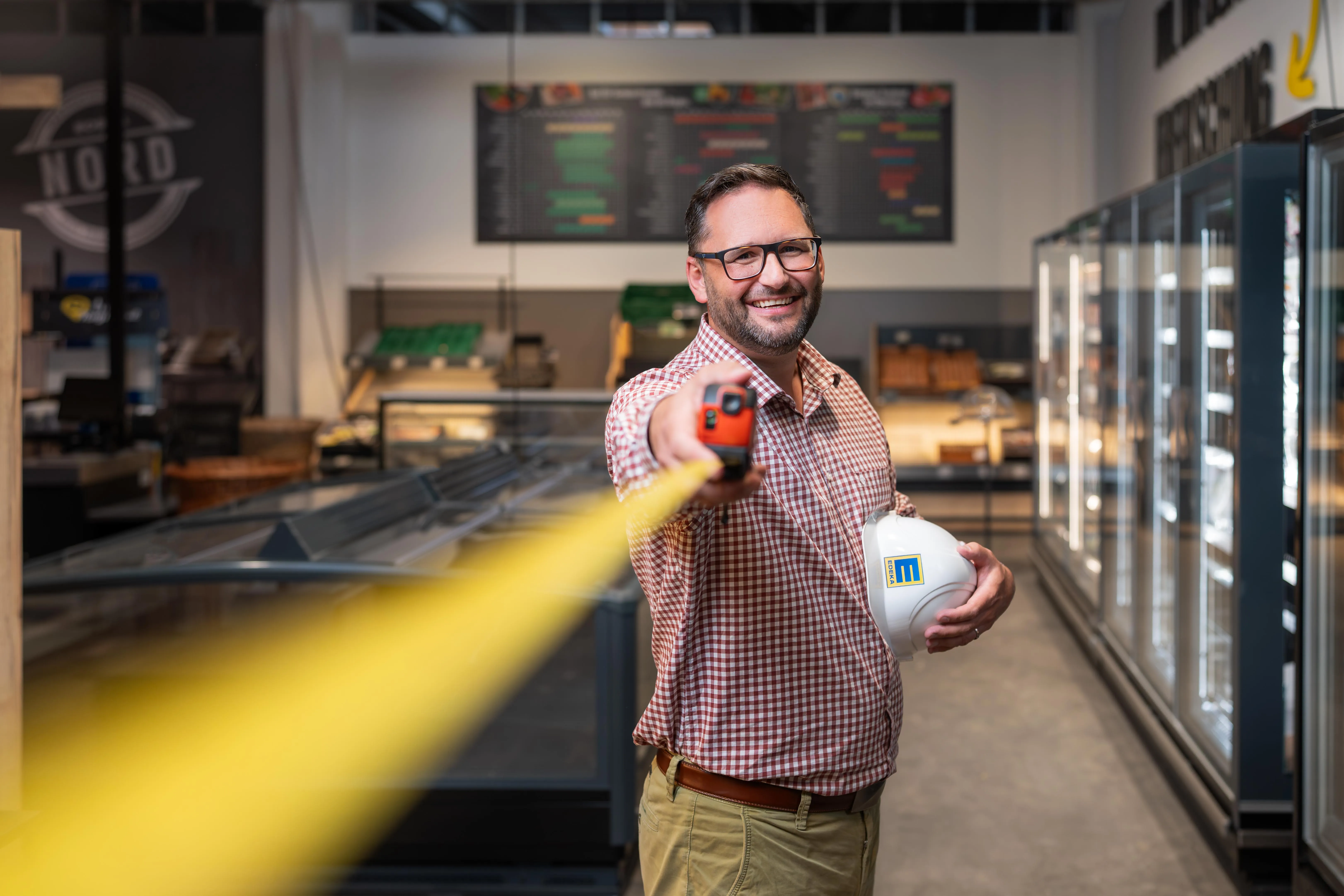 Ein EDEKA-Lieferwagen vor einem Gebäude mit dem Schriftzug "Wir lieben Lebensmittel" auf der Fassade.