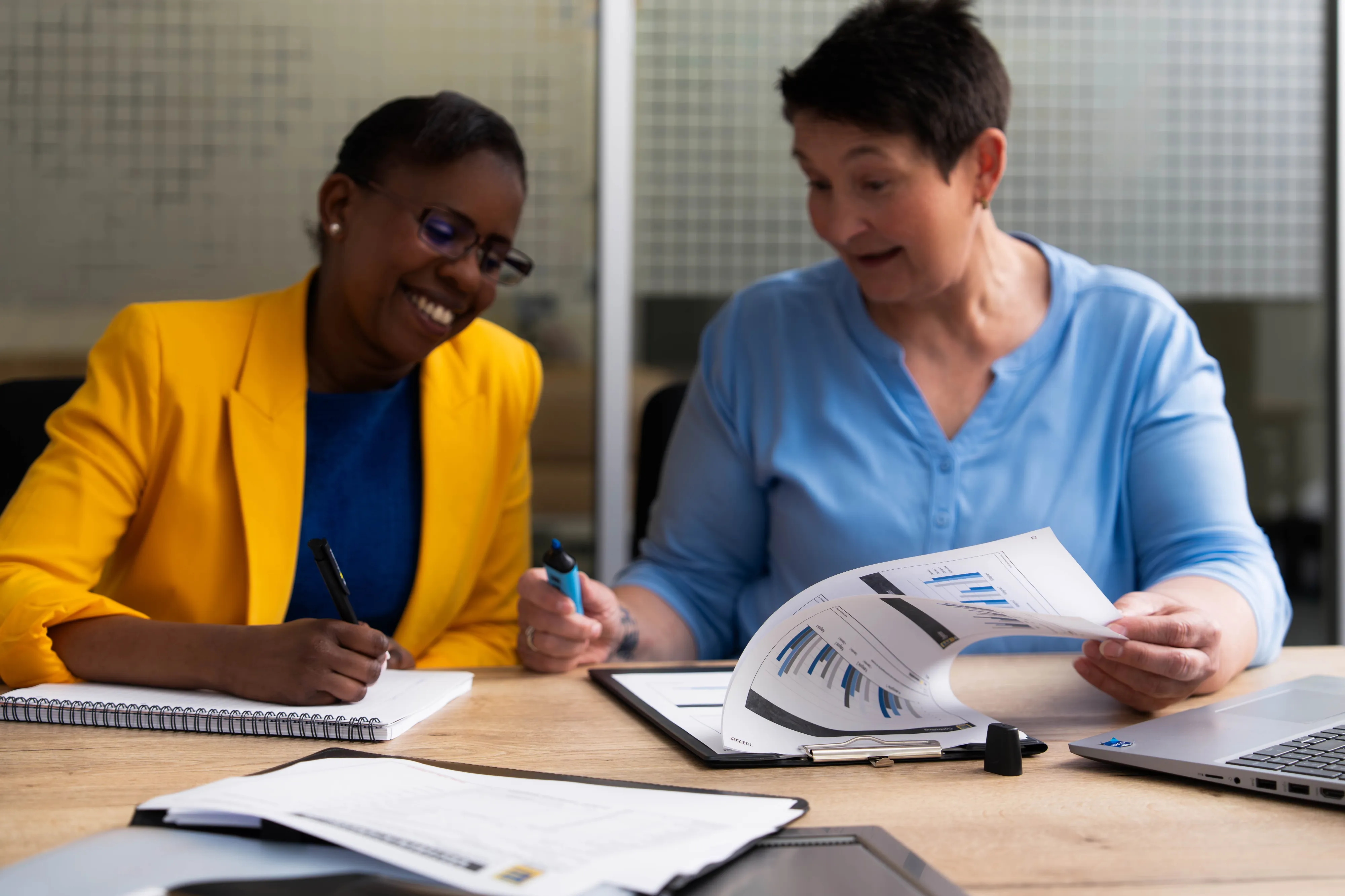 Ein lächelnder Mann sitzt an einem Schreibtisch im Büro von EDEKA Nord, mit einem Computer im Hintergrund.