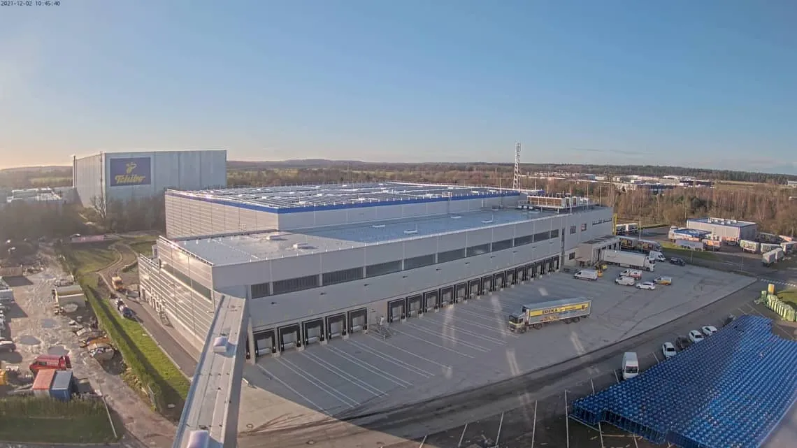 Großes EDEKA Nordwest Logistikzentrum mit LKWs und Ladezonen bei sonnigem Wetter – hier startest Du Deine Karriere im Handel.