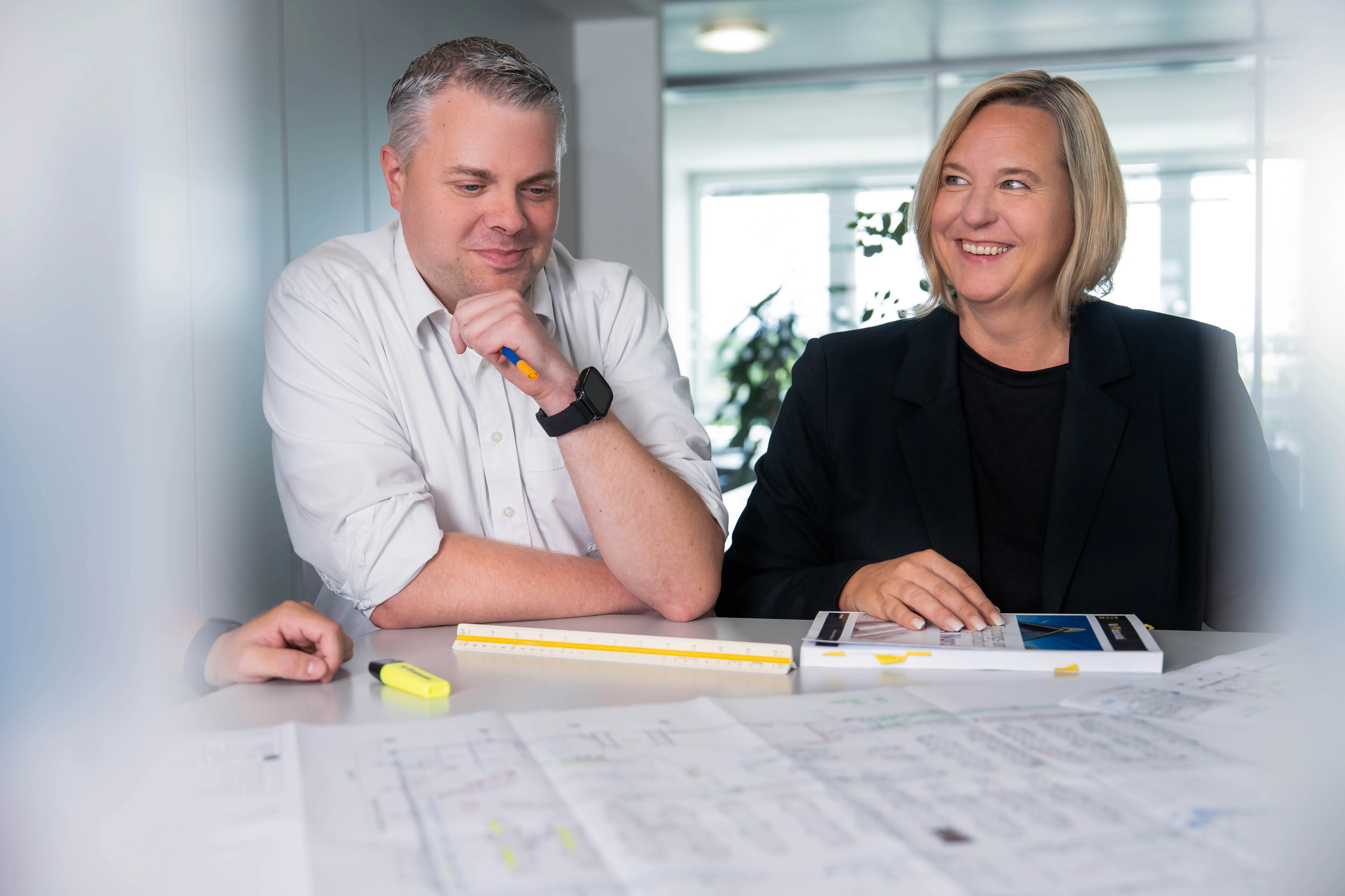 Eine Frau arbeitet an einem Laptop in einem Büro. Im Hintergrund ist ein Bild eines EDEKA-Geschäfts zu sehen.