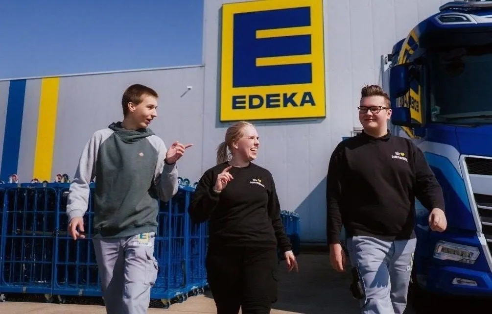 3 Azubis laufen aus einer Edeka Filiale