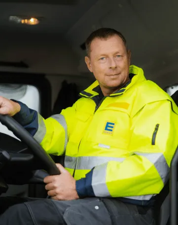 Ein Berufskraftfahrer im EDEKA Nordwest-Outfit sitzt am Steuer eines Lkw und schaut freundlich in die Kamera.
