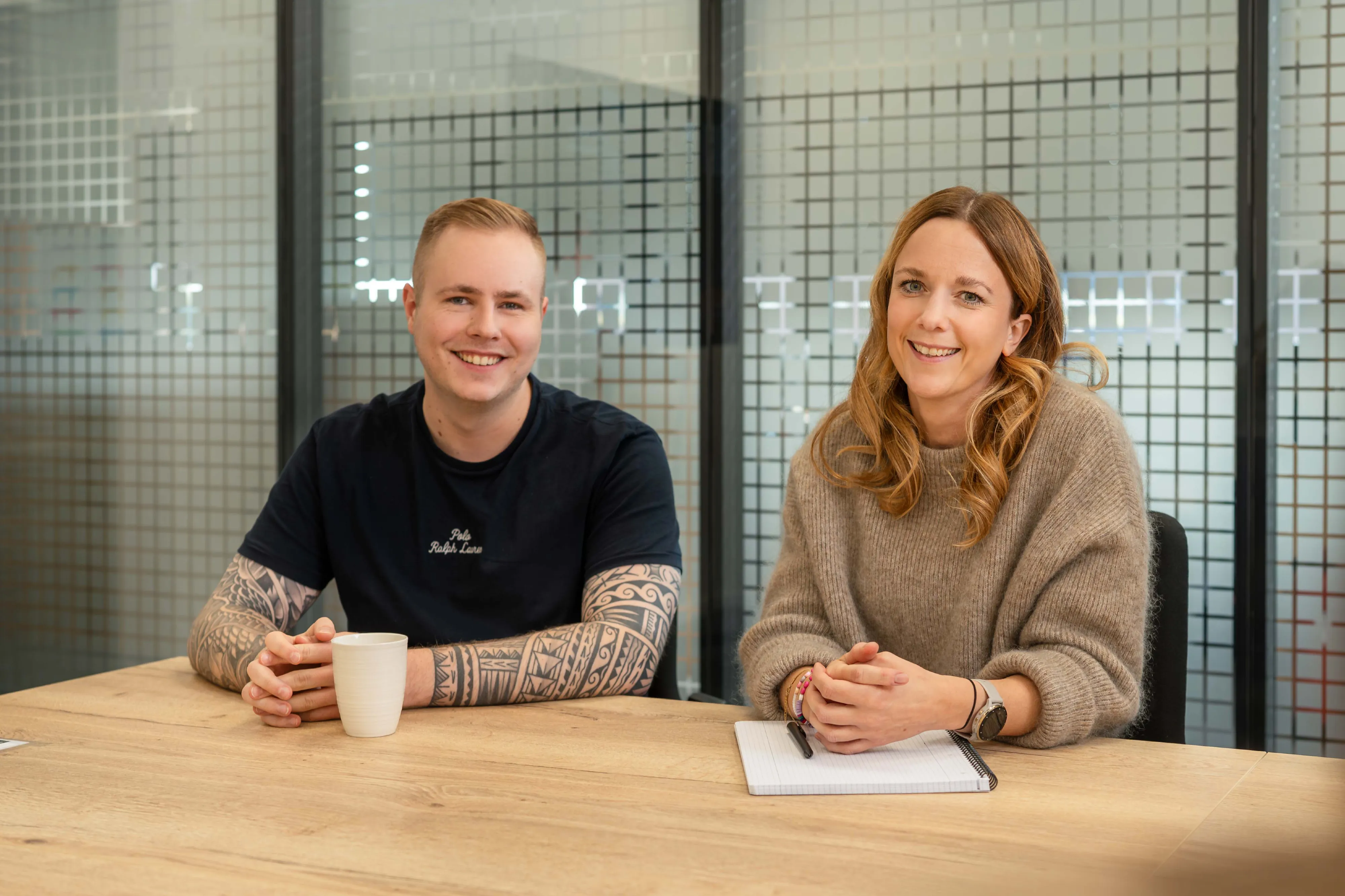 Eine lächelnde Frau in einem gelben Pullover steht in einem modernen Büro bei EDEKA Handelsgesellschaft Nord mbH.