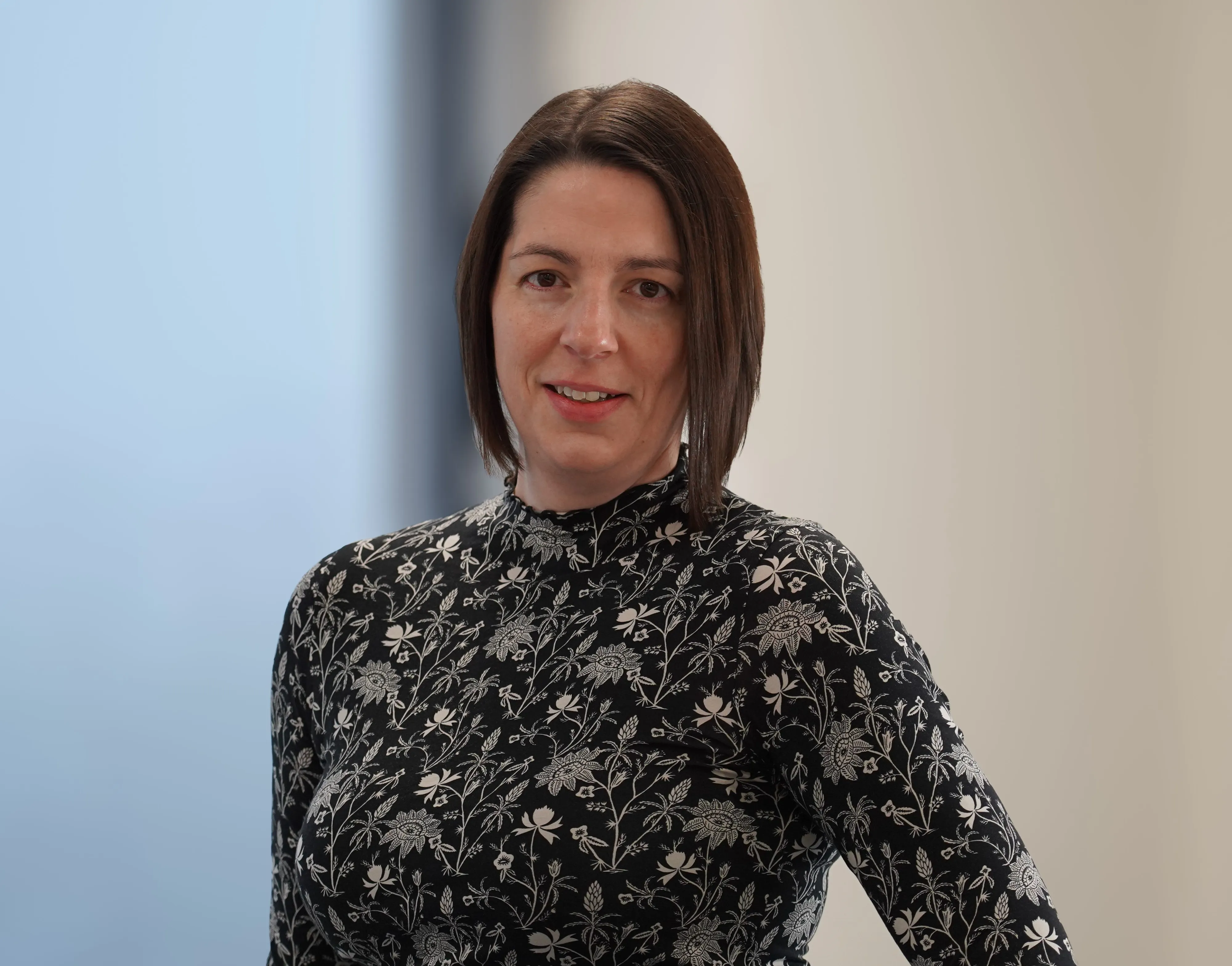 Eine lächelnde Frau steht vor Pflanzen, geeignet für die Karriereseite von EDEKA Handelsgesellschaft Nord mbH im Einzelhandel.