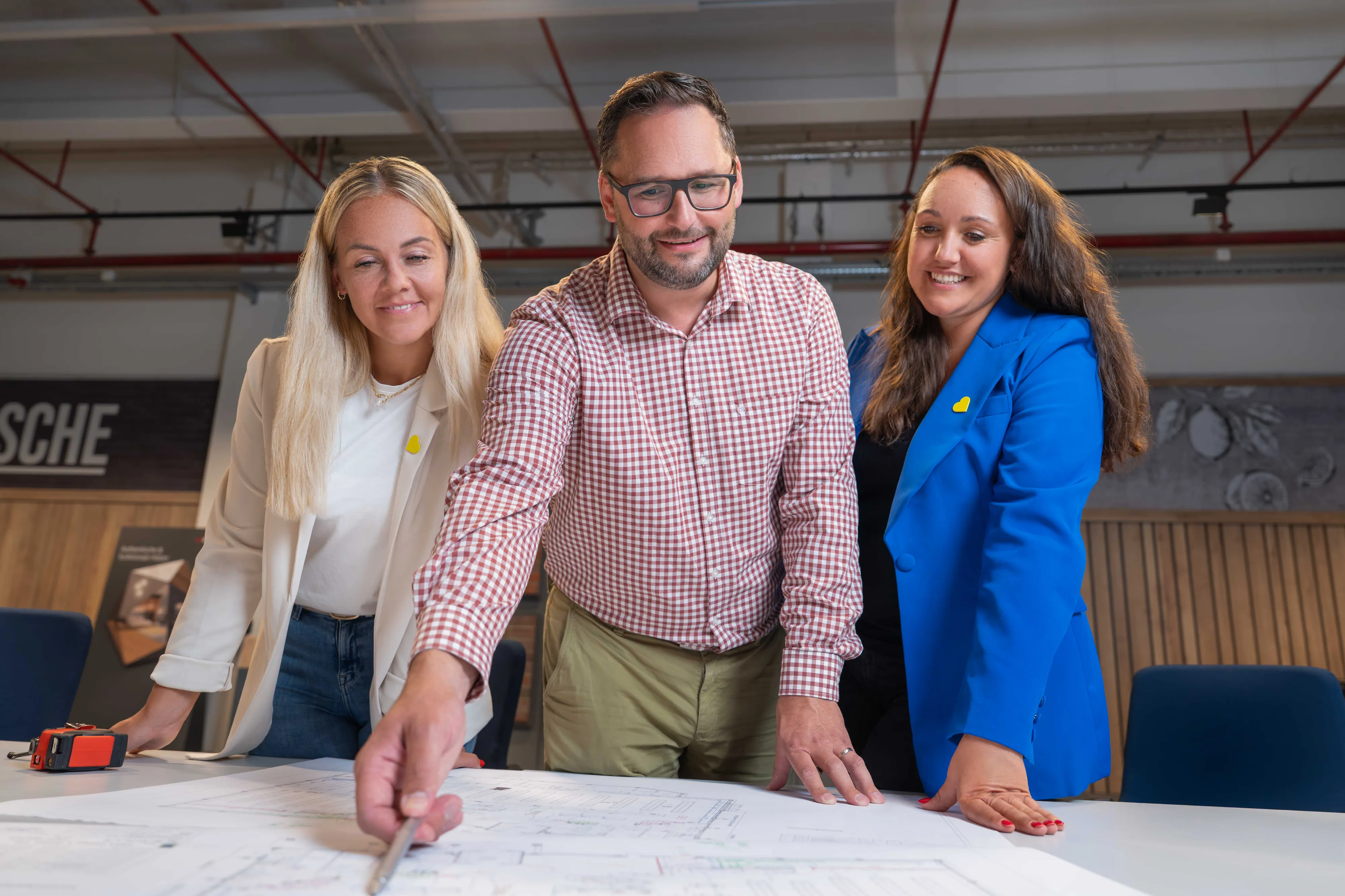 Drei Kollegen diskutieren über Dokumente an einem Tisch im Büro von EDEKA Handelsgesellschaft Nord.