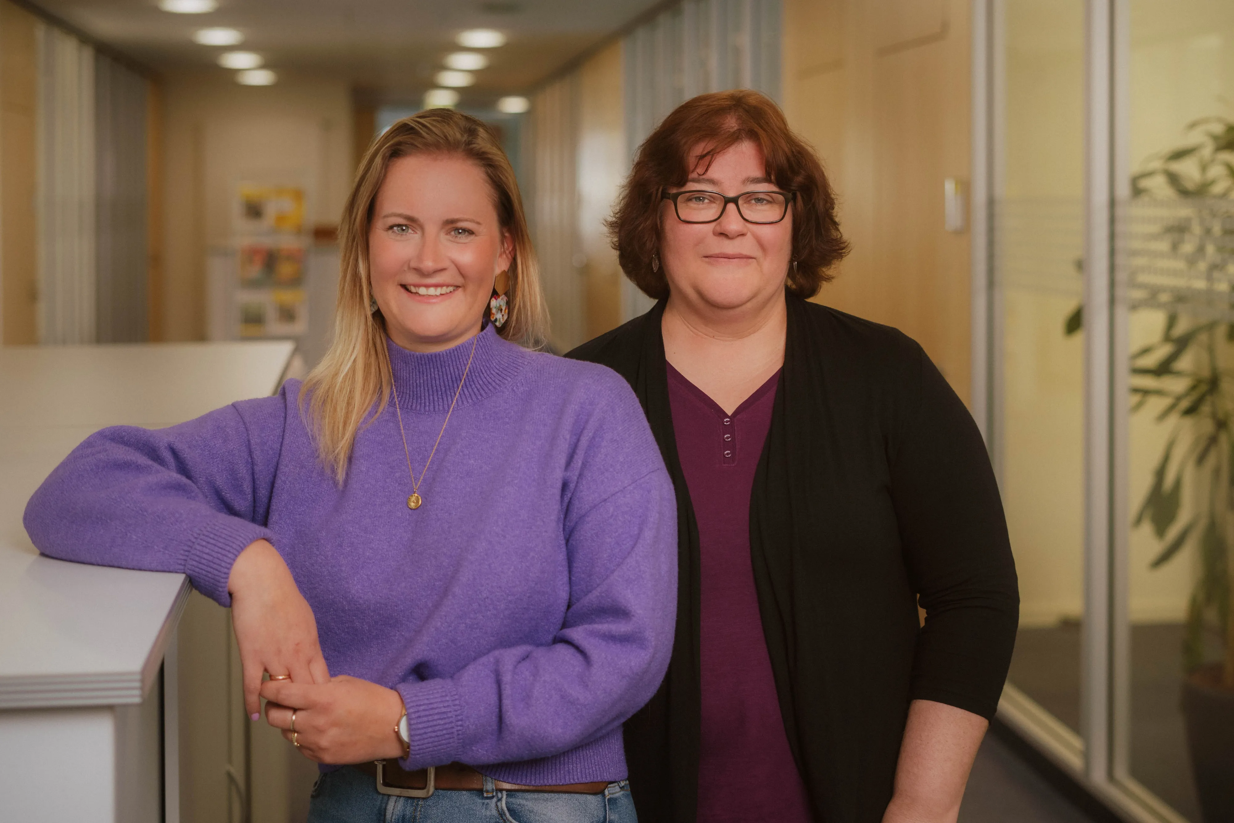 Zwei lächelnde Frauen in einem modernen Büro von EDEKA Nord, die Teamarbeit und Freundlichkeit ausstrahlen.