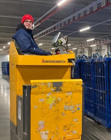 Du steuerst einen gelben Gabelstapler im EDEKA-Lager und bewegst Waren für den Einzelhandel.