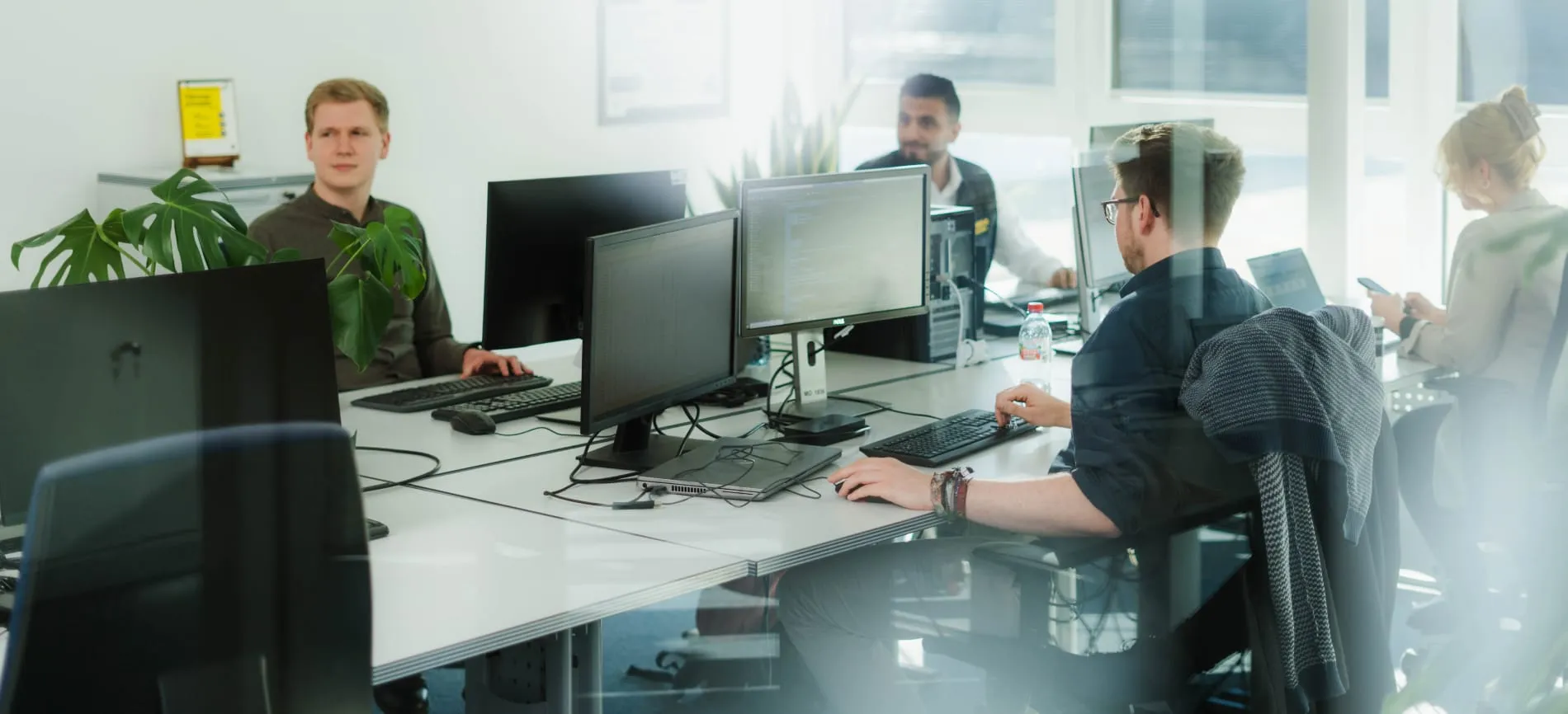 Vier Kollegen arbeiten gemeinsam an Computern in einem modernen, hellen EDEKA Nordwest Büro.