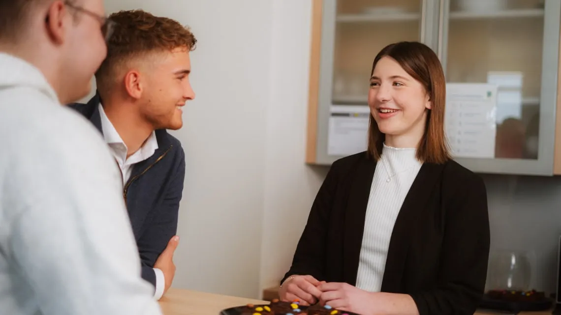 Drei junge Kollegen unterhalten sich lachend in einer Büroküche bei EDEKA Nordwest – hier bist Du im Team willkommen.
