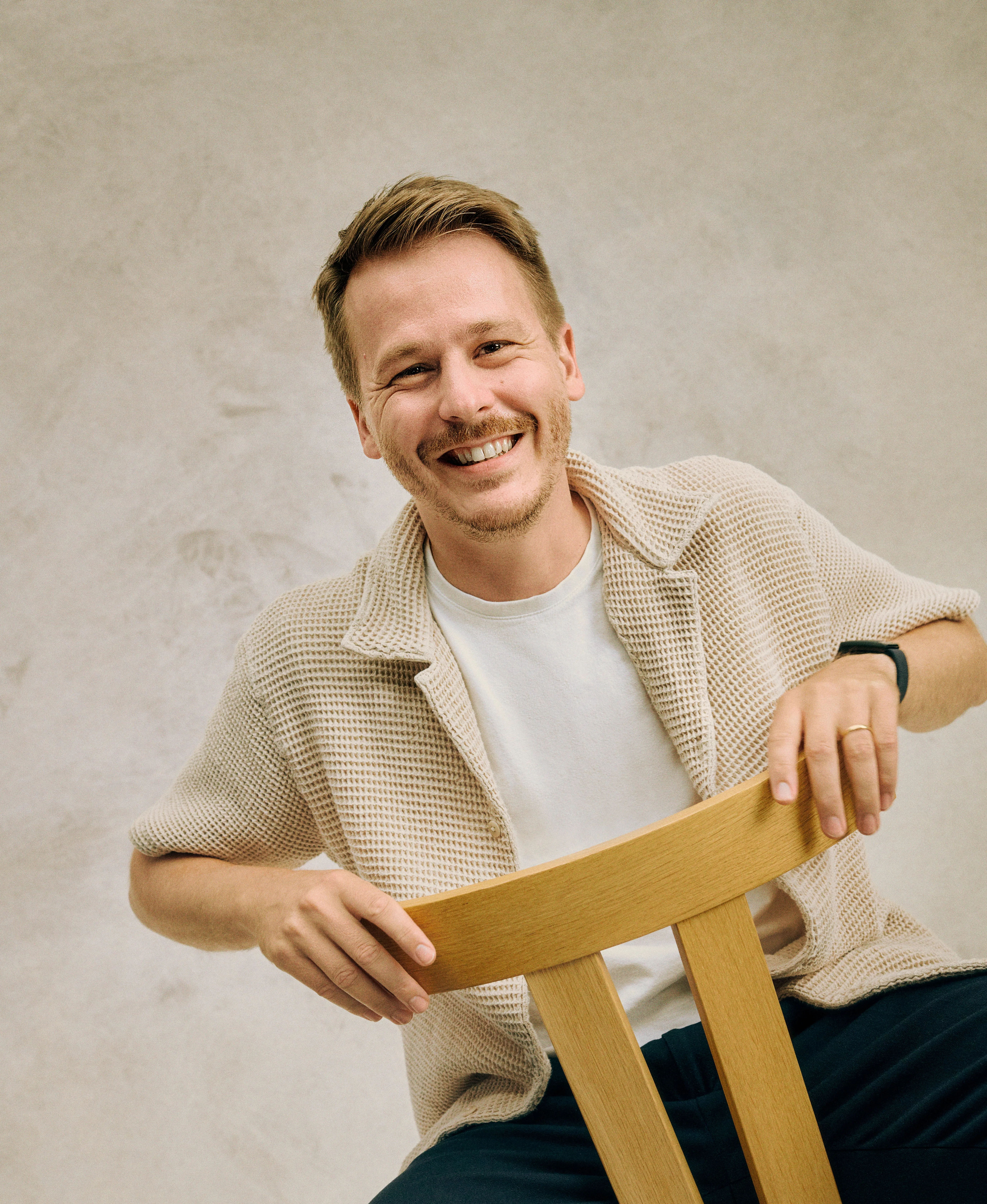 Mann auf Stuhl, der in Kamera schaut