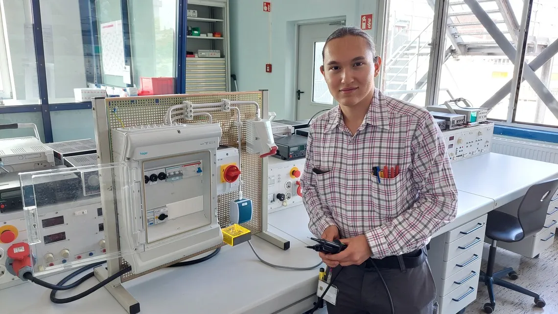 Junger Techniker prüft elektrische Anlagen im Labor von Evonik – Deine Karriere im Bereich Energie und Versorgung.