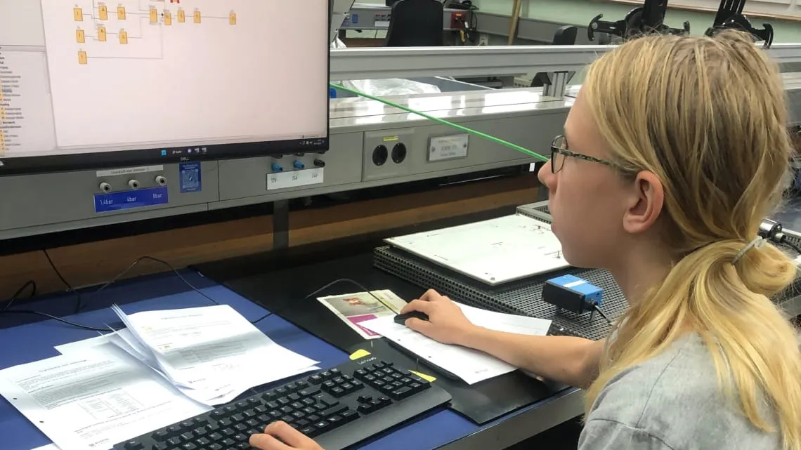 Junge Person arbeitet am Computer mit technischer Software im Labor bei Evonik im Bereich Energie und Utilities.