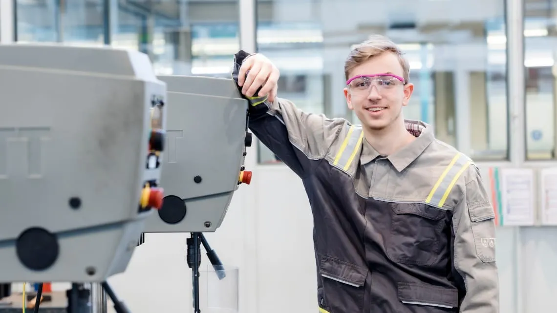 Junger Mann in Schutzkleidung arbeitet an einer Maschine bei Evonik im Bereich Energie und Versorgung.
