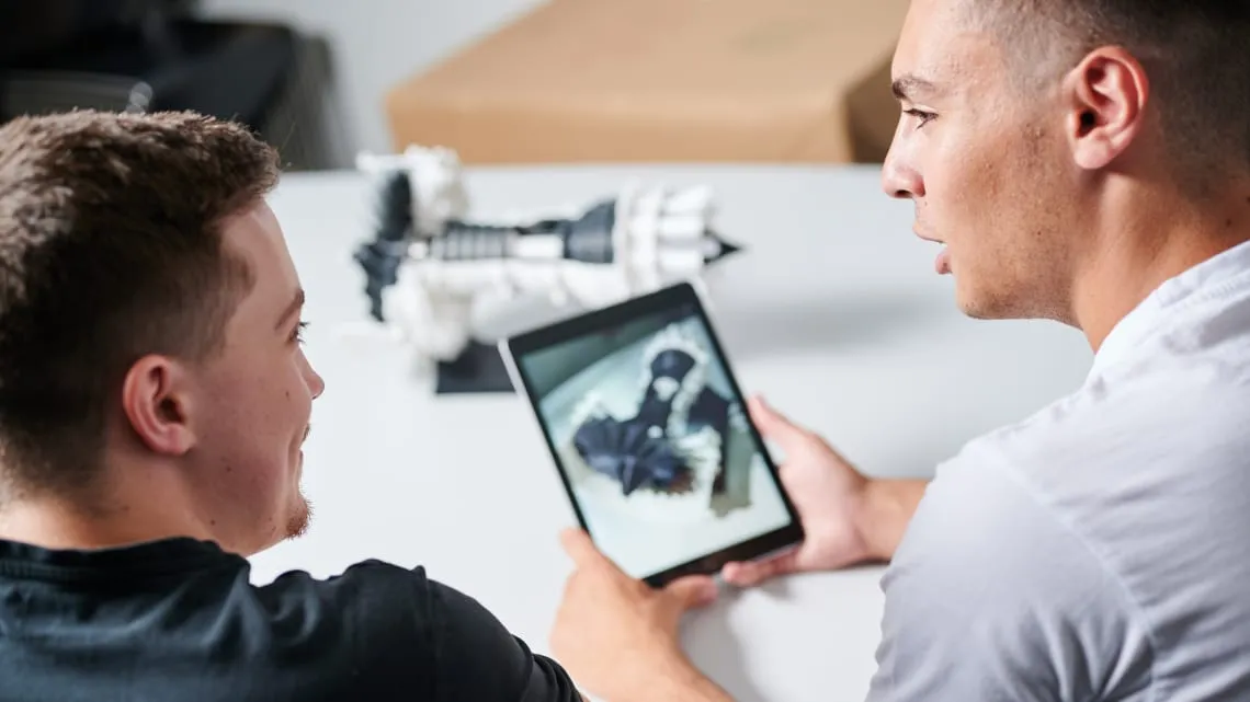 Zwei junge Männer betrachten gemeinsam ein technisches 3D-Modell auf einem Tablet, ideal für Deinen Einstieg bei Evonik.