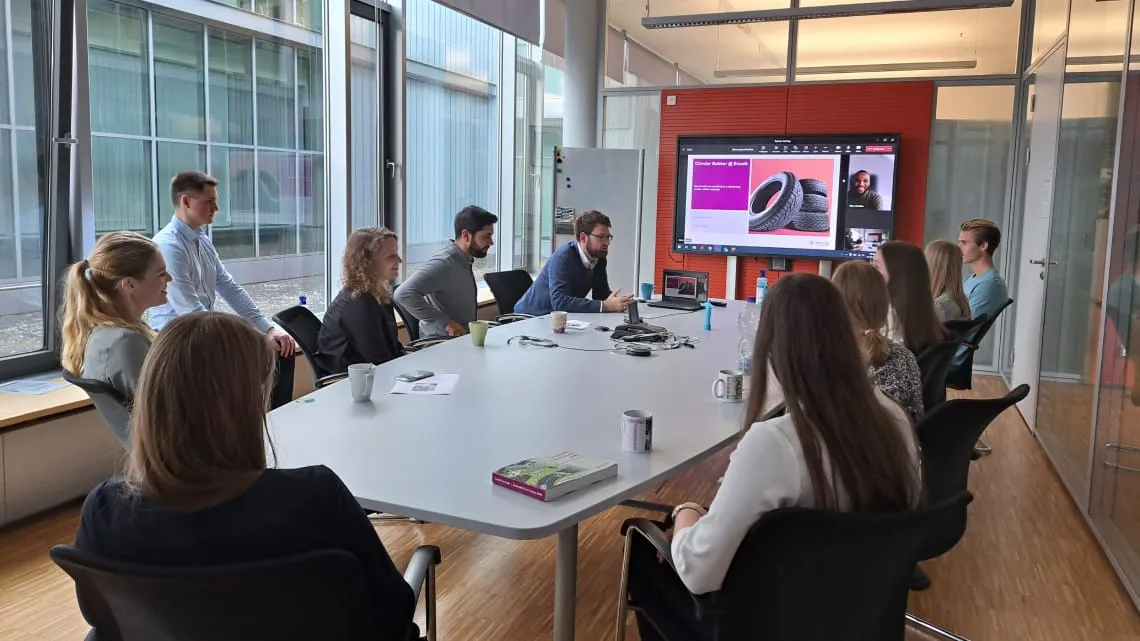 Junges Team bei Evonik diskutiert innovative Energielösungen in einem modernen Konferenzraum mit Videopräsentation.