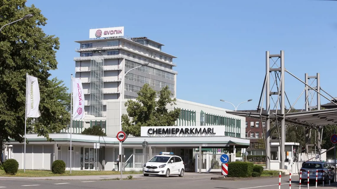 Das Bild zeigt den Eingang des Chemieparks Marl mit Evonik-Gebäude und Fahnen, die Dich zu einer Karriere im Energiesektor einladen.