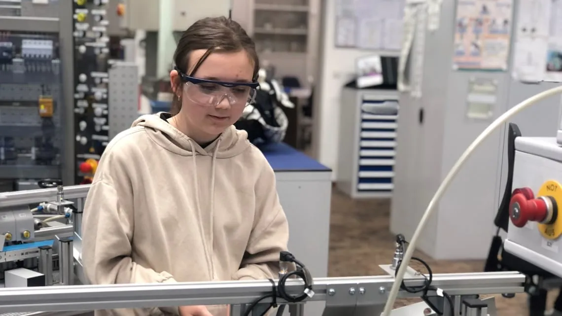Junges Mädchen mit Schutzbrille arbeitet an einer technischen Anlage im Labor bei Evonik.
