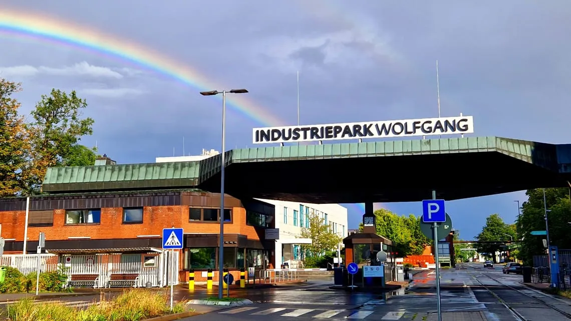 Eingang zum Industriepark Wolfgang mit Regenbogen am Himmel – hier kannst Du Deine Karriere bei Evonik starten.