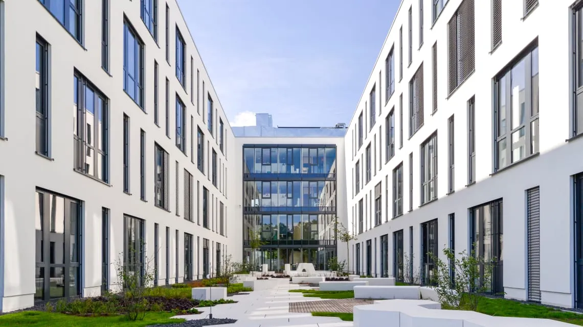 Moderner Bürokomplex von Evonik mit begrüntem Innenhof, wo Du in der Energie- und Versorgungsbranche arbeiten kannst.