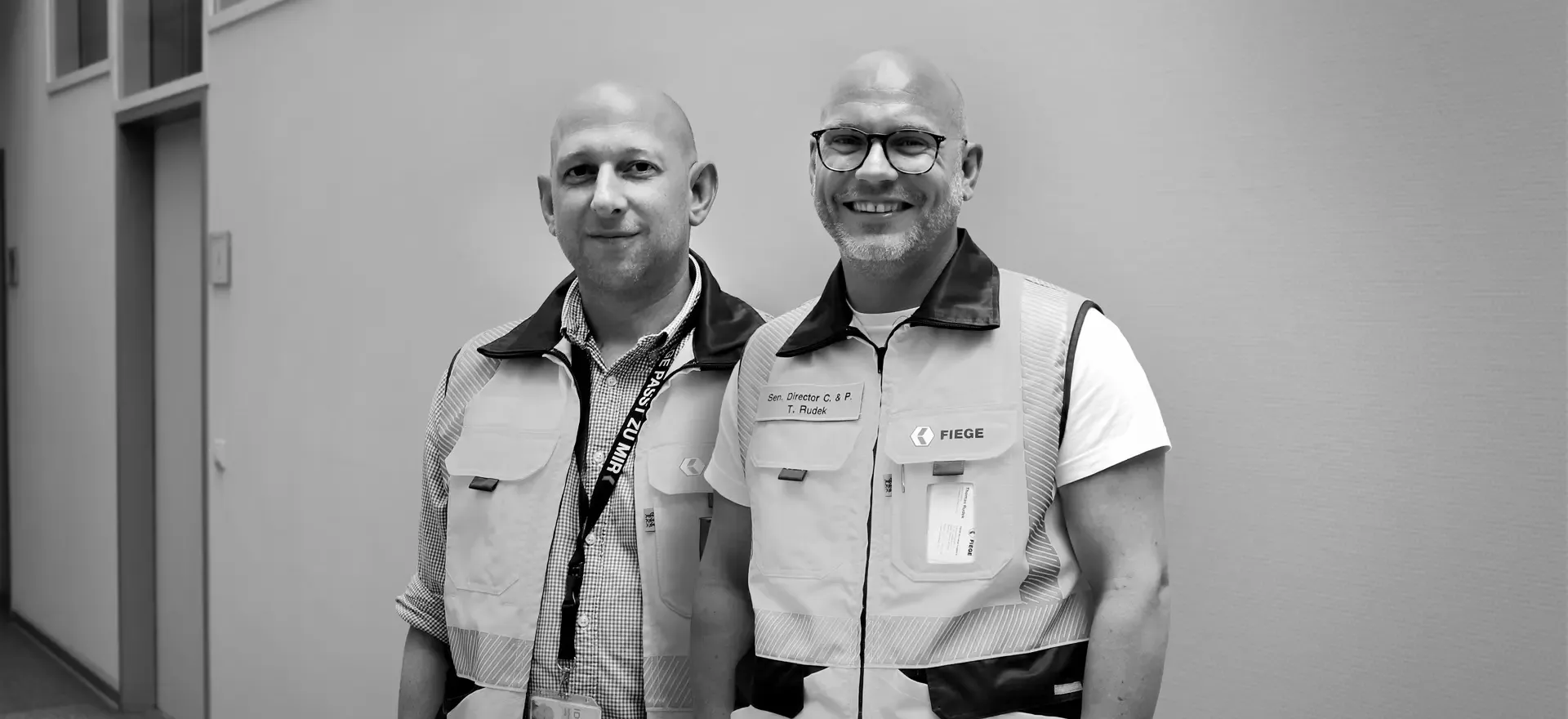 Vier Mitarbeiter in Sicherheitswesten vor einem FIEGE-Logistikzentrum.