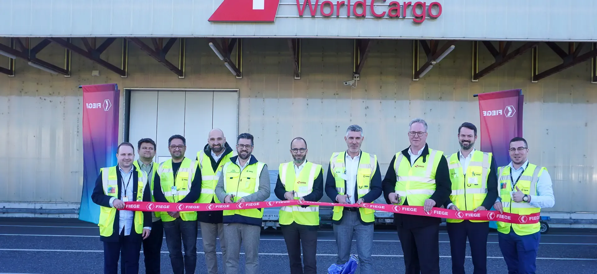 Luftaufnahme eines großen FIEGE-Logistikzentrums mit mehreren Lagerhallen und LKWs auf dem Gelände.