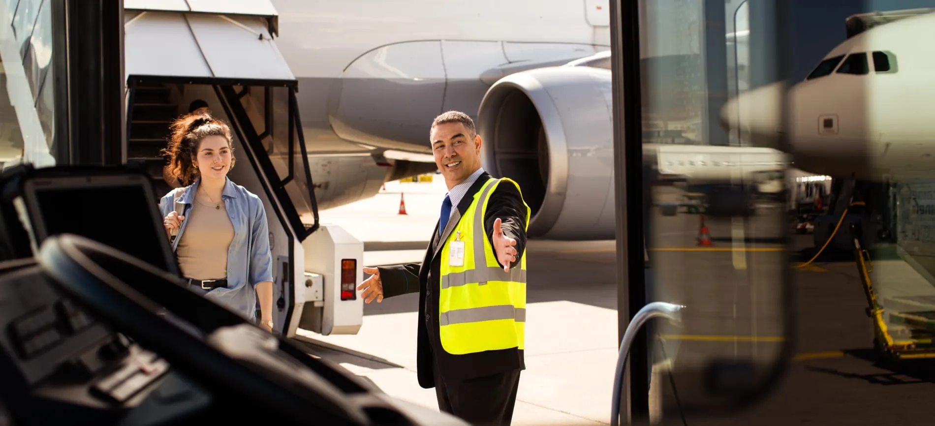 Ein Mitarbeiter begrüßt Dich freundlich am Flughafen, während Du vom Flugzeug zum Bus gehst.