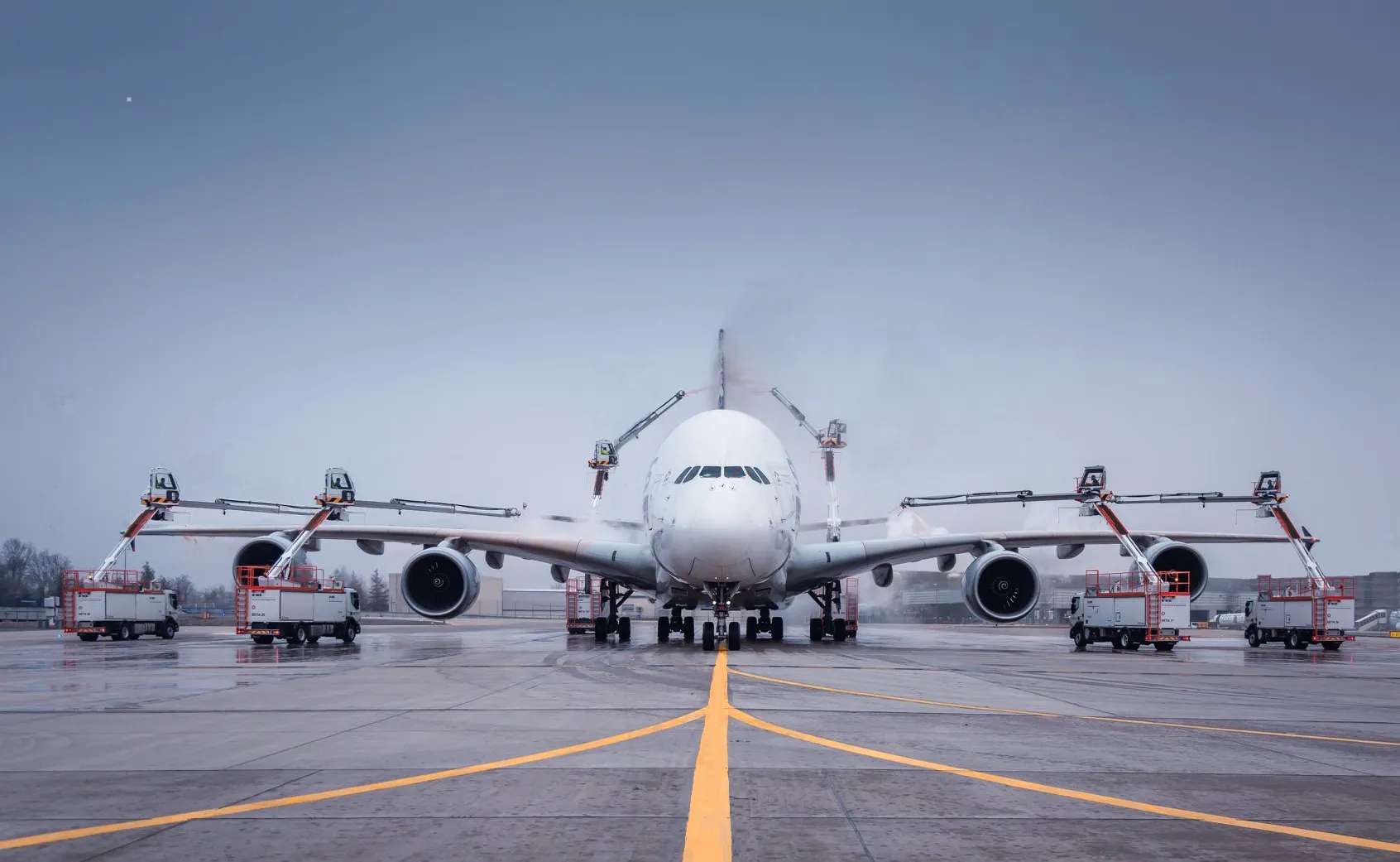 Du siehst eine Fraport-Mitarbeiterin mit Warnweste und Headset lächelnd auf dem Flughafenvorfeld vor einem Flugzeug.