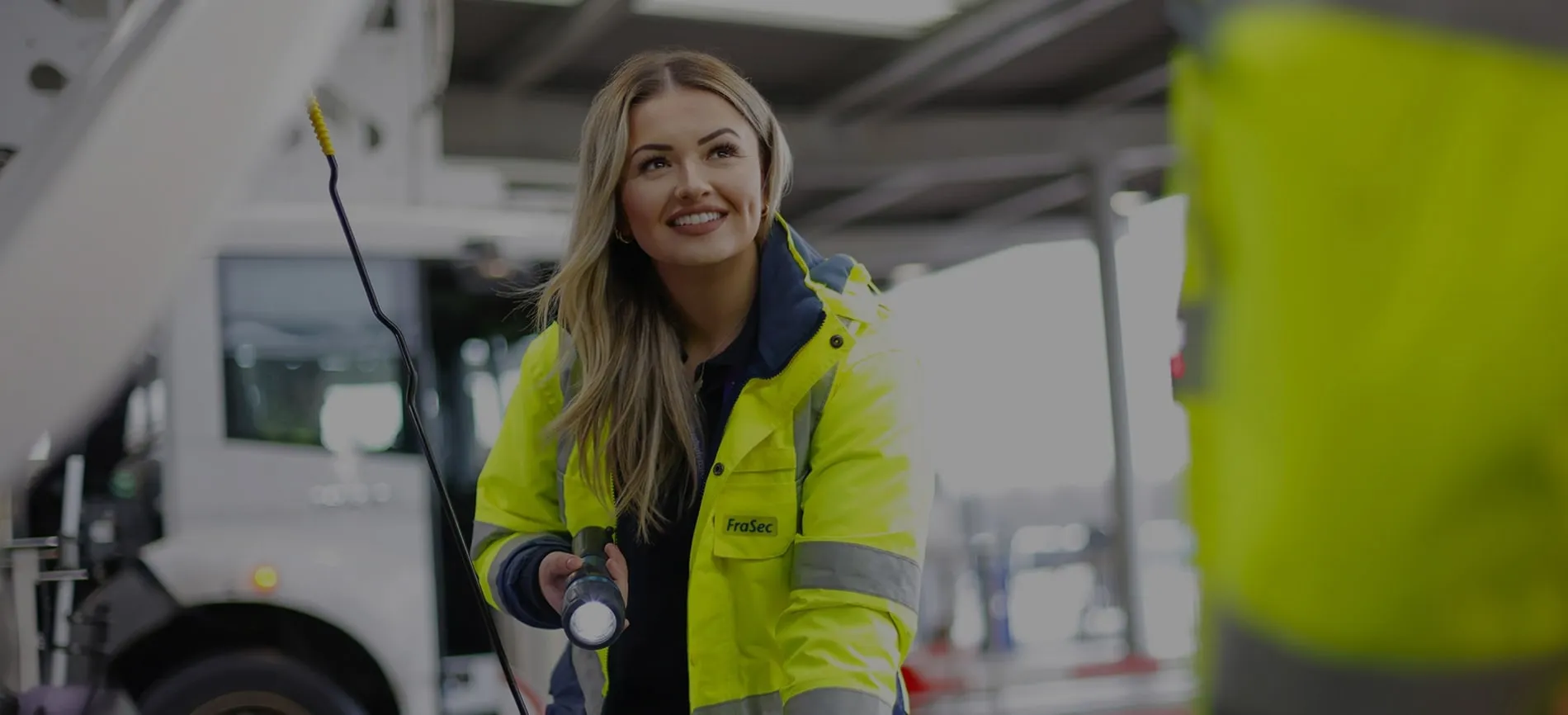 Junge Frau im gelben Sicherheitsjacke arbeitet mit Taschenlampe im Logistikbereich am Flughafen.