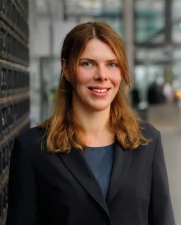 Junge Frau im Business-Outfit lächelt freundlich in einer modernen Flughafenhalle von Fraport AG.