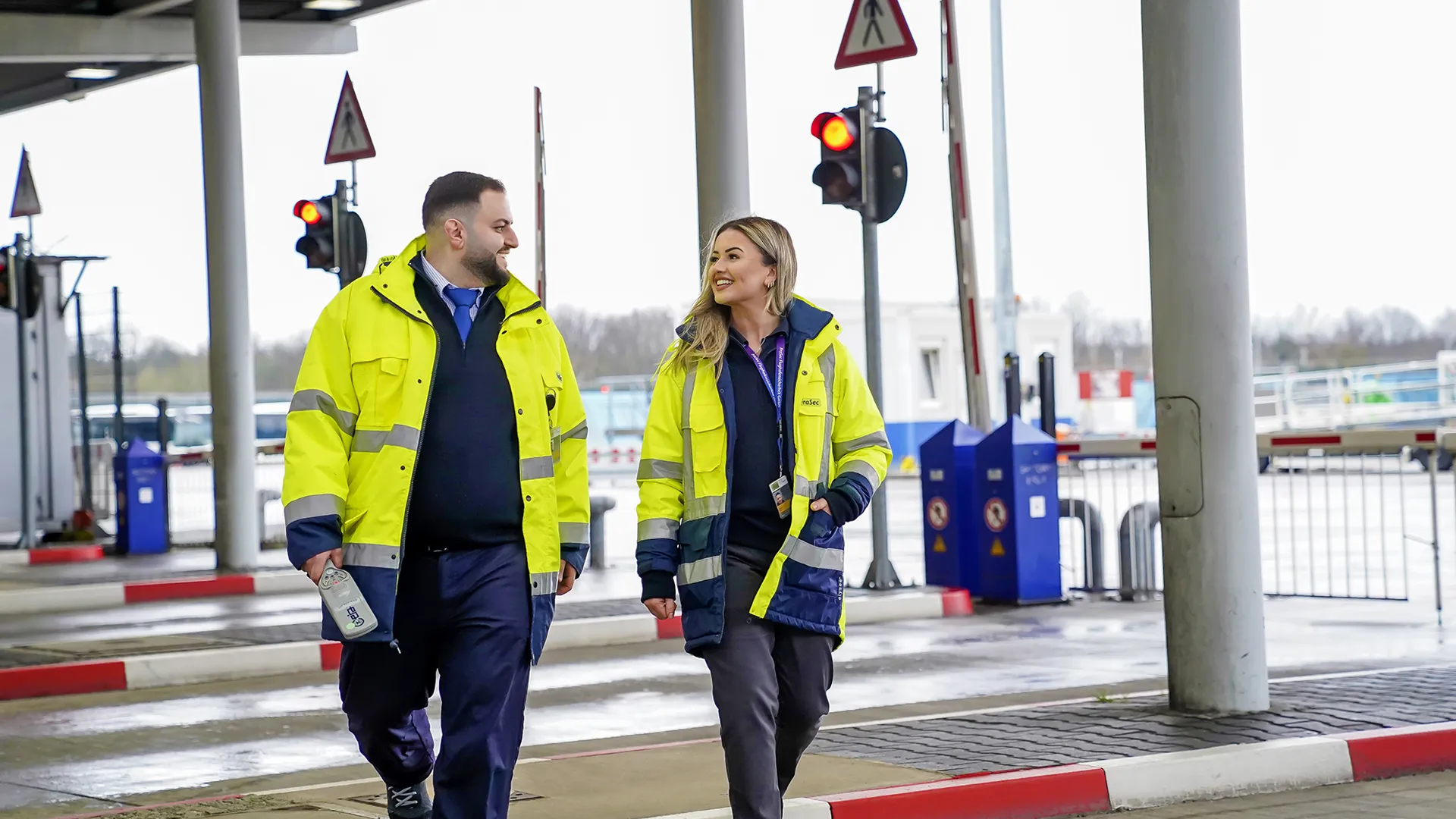 Zwei Mitarbeitende im gelben Sicherheitsoverall unterhalten sich freundlich auf dem Flughafengelände von Fraport.
