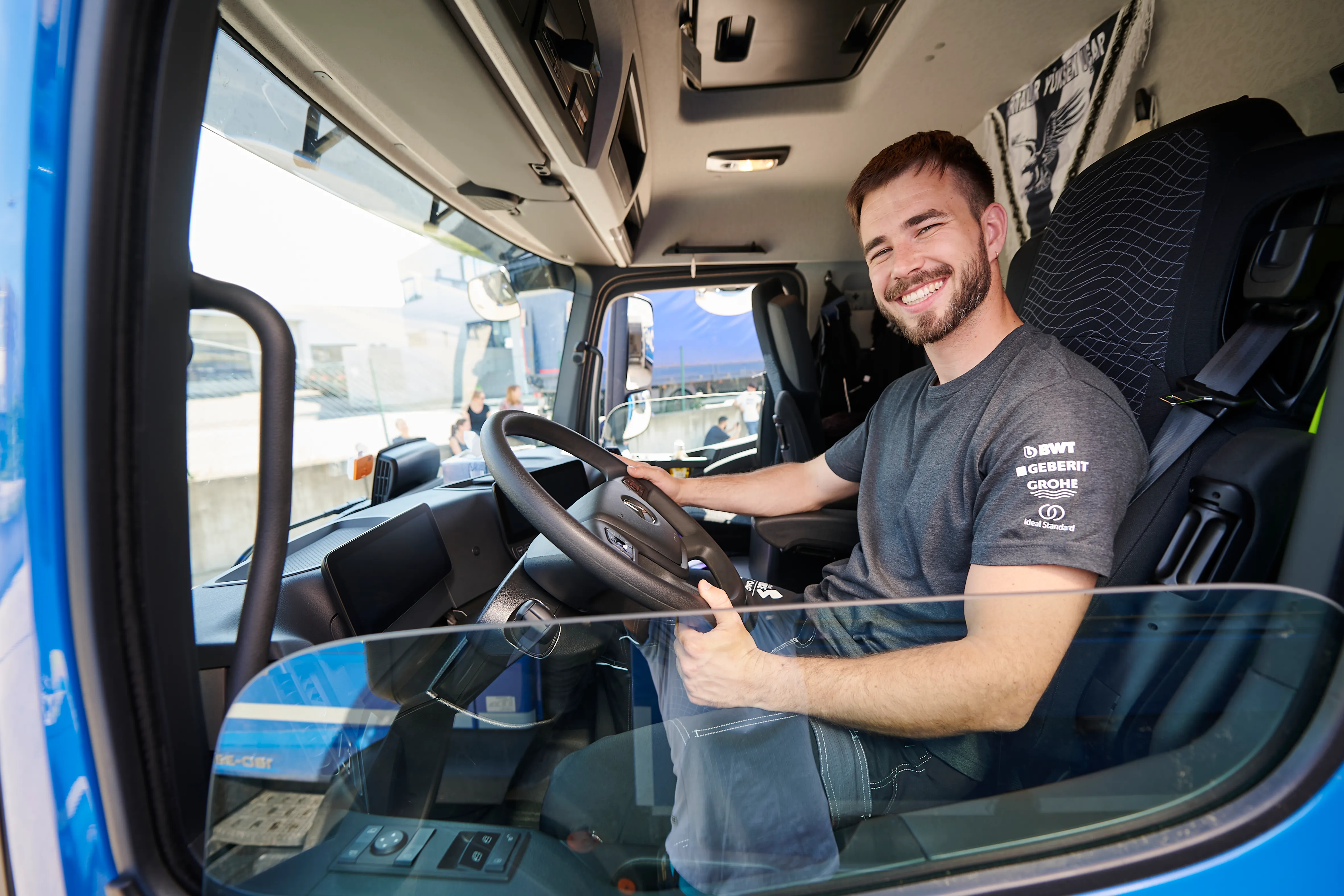 Ein lächelnder Mann sitzt am Steuer eines LKWs, bereit für die Auslieferung bei Frauenthal Handel Gruppe.