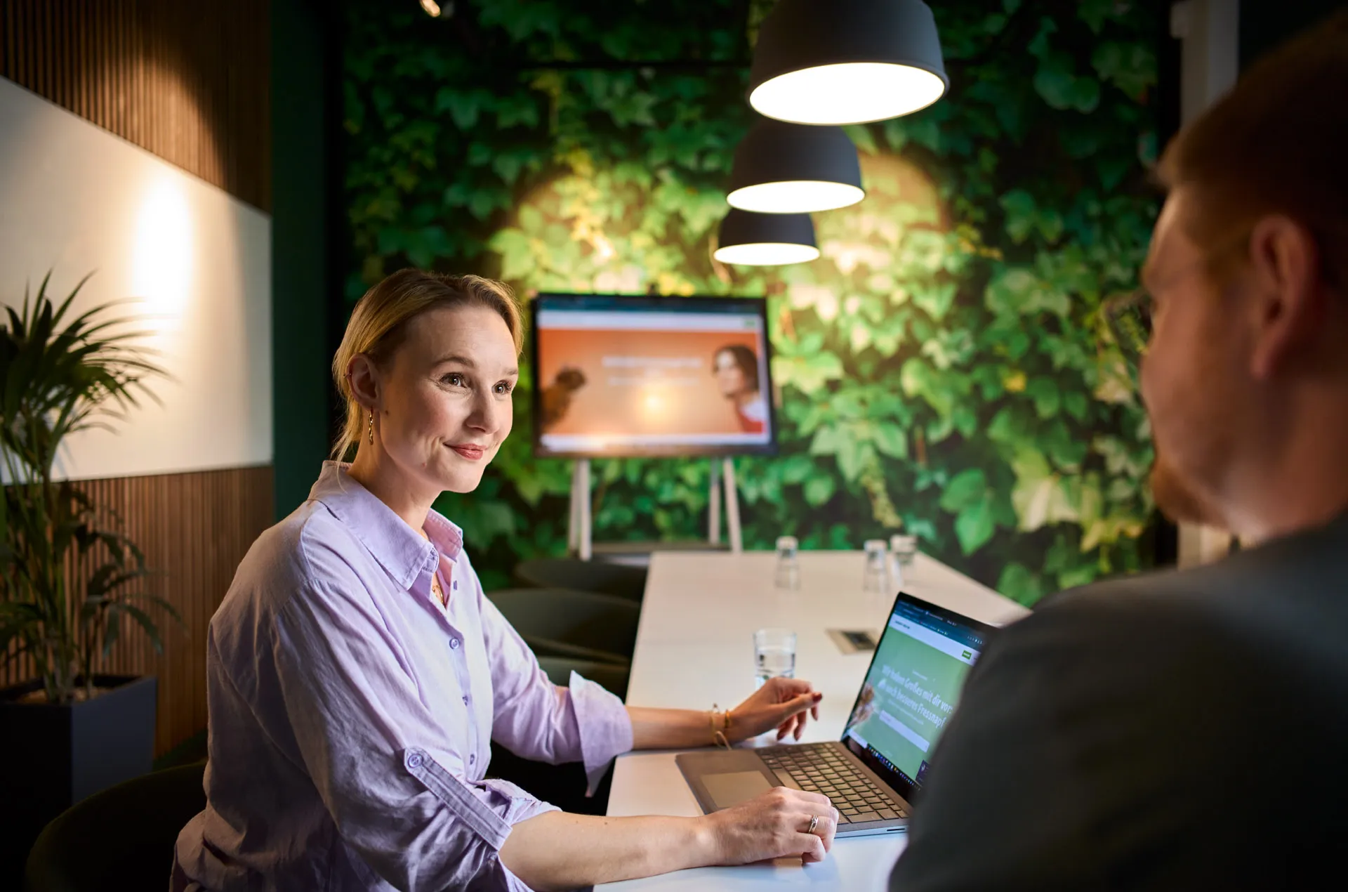 Ein Teammeeting bei Fressnapf Holding SE: Drei Personen diskutieren in einem modernen Büro mit Pflanzen und einem Bildschirm im Hintergrund.