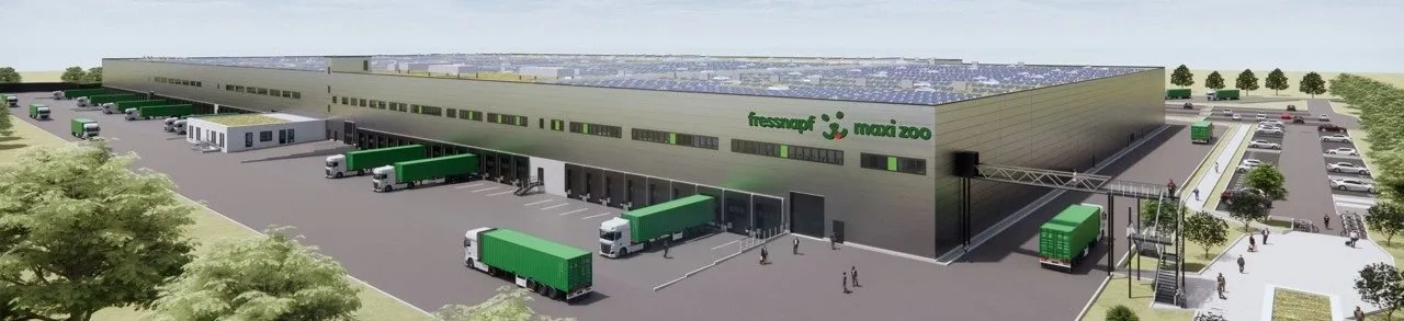 Eine moderne Fressnapf-Logistikhalle mit grünen LKWs im Ladebereich. Menschen bewegen sich auf dem Gelände.