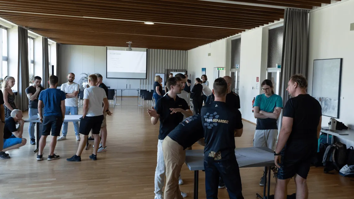 Mehrere Teams von Gepardec IT Services tauschen sich locker bei einem Workshop in einem modernen Seminarraum aus.