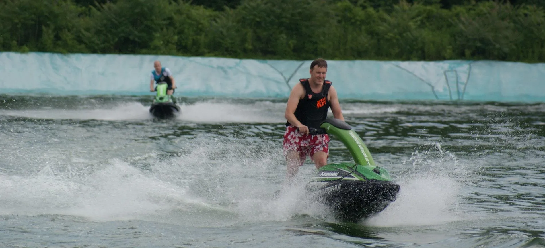 Zwei Kollegen von Gepardec fahren gemeinsam Jetski bei einem Teamevent auf dem Wasser und haben sichtlich Spaß.