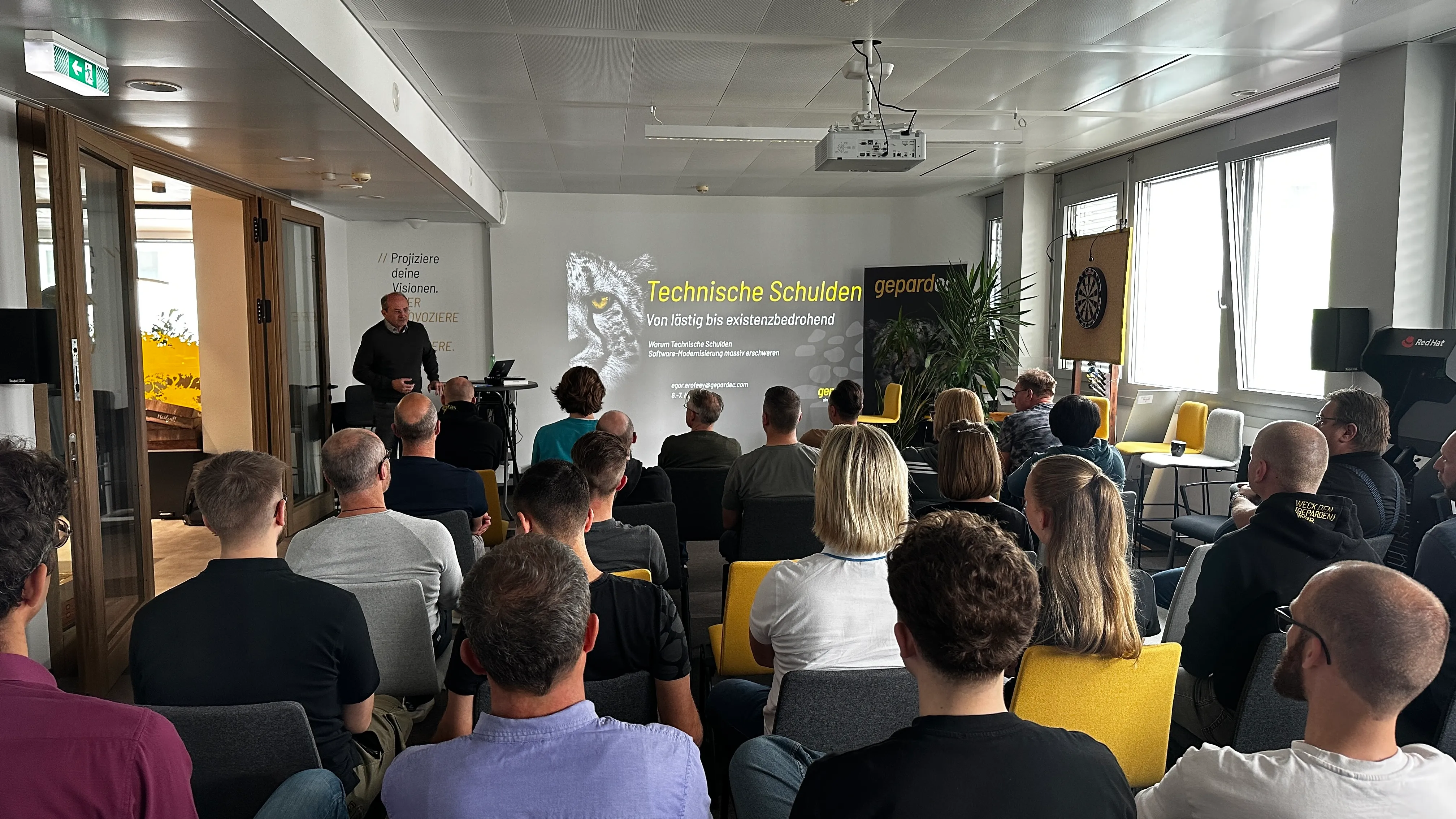 Ein Vortrag bei Gepardec IT Services GmbH über "Technische Schulden". Teilnehmer sitzen in einem modernen Konferenzraum und hören zu.