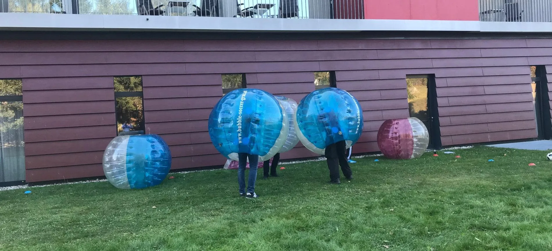 Kollegen von Gepardec spielen gemeinsam Bubble Soccer auf der Wiese vor dem Bürogebäude.