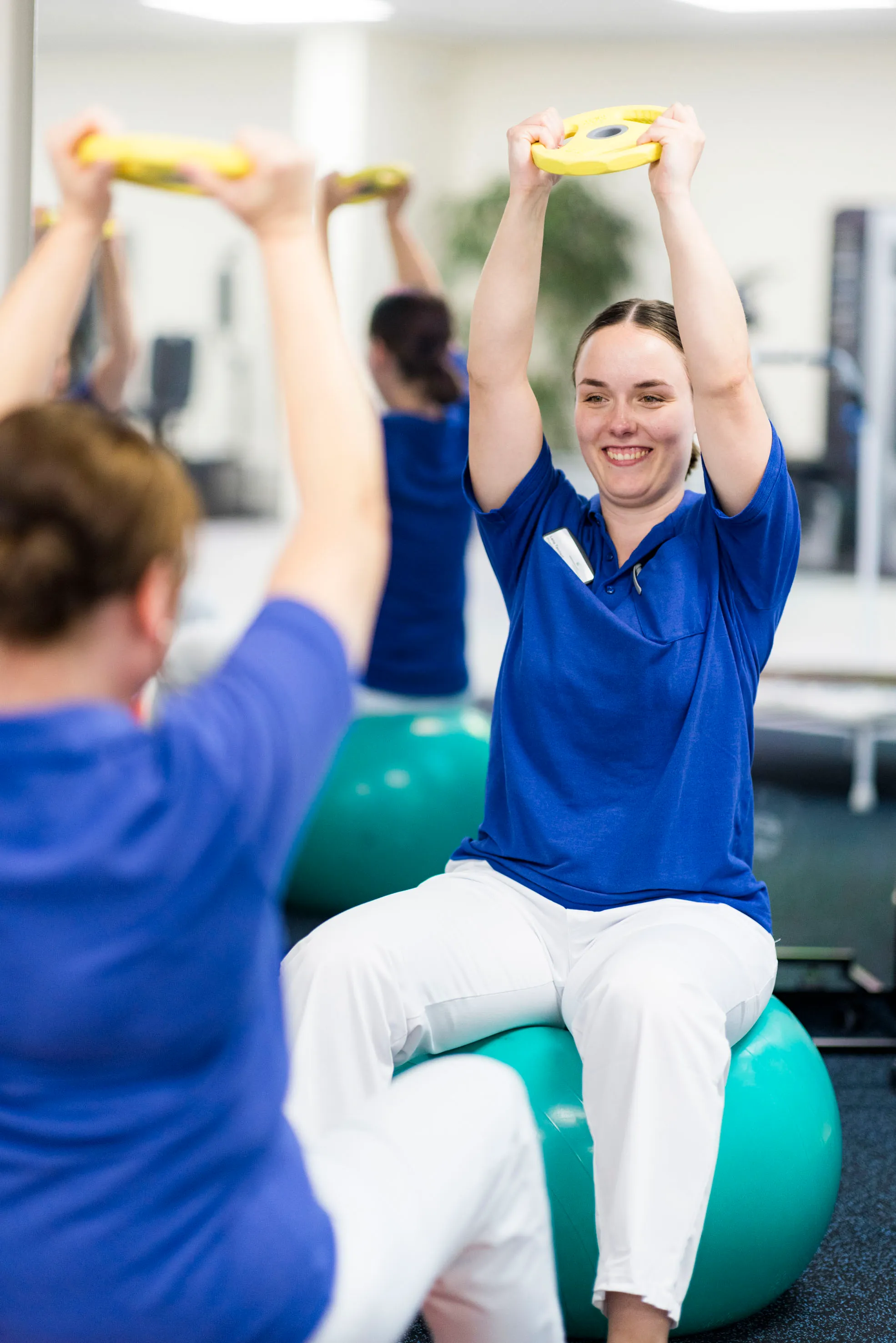 Therapeutin in blauer Arbeitskleidung betreut einen Patienten