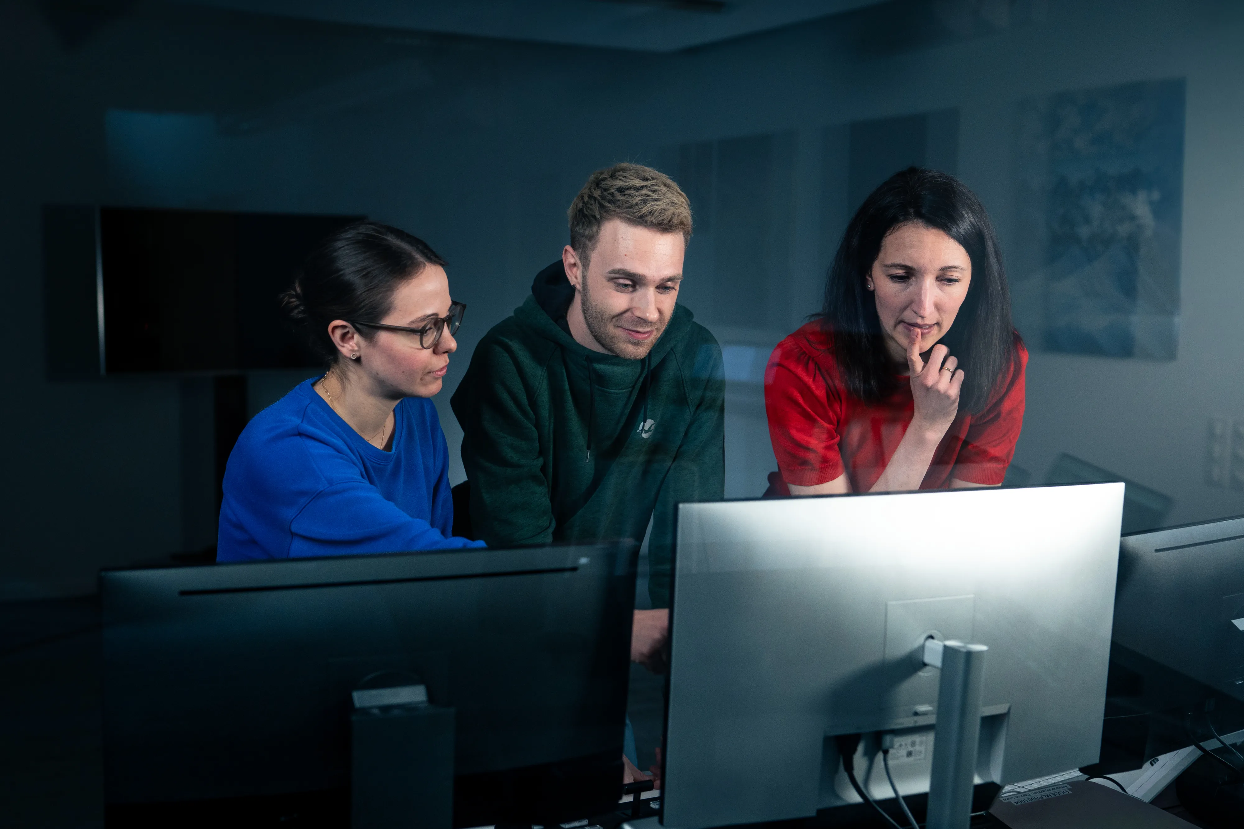 Three teammates brainstorming together in front of a computer screen