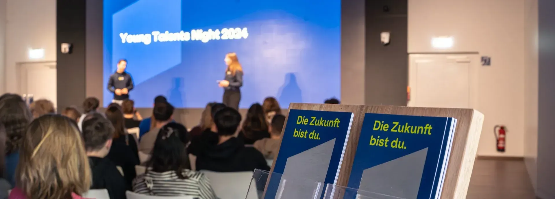 Präsentation bei der Young Talents Night 2024 mit Flyer im Vordergrund, Aufschrift 'Die Zukunft bist du.'