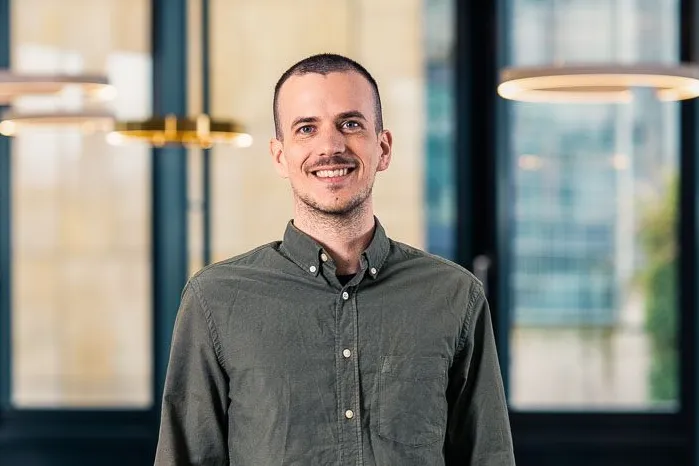 You can see a friendly smiling man in a grey shirt