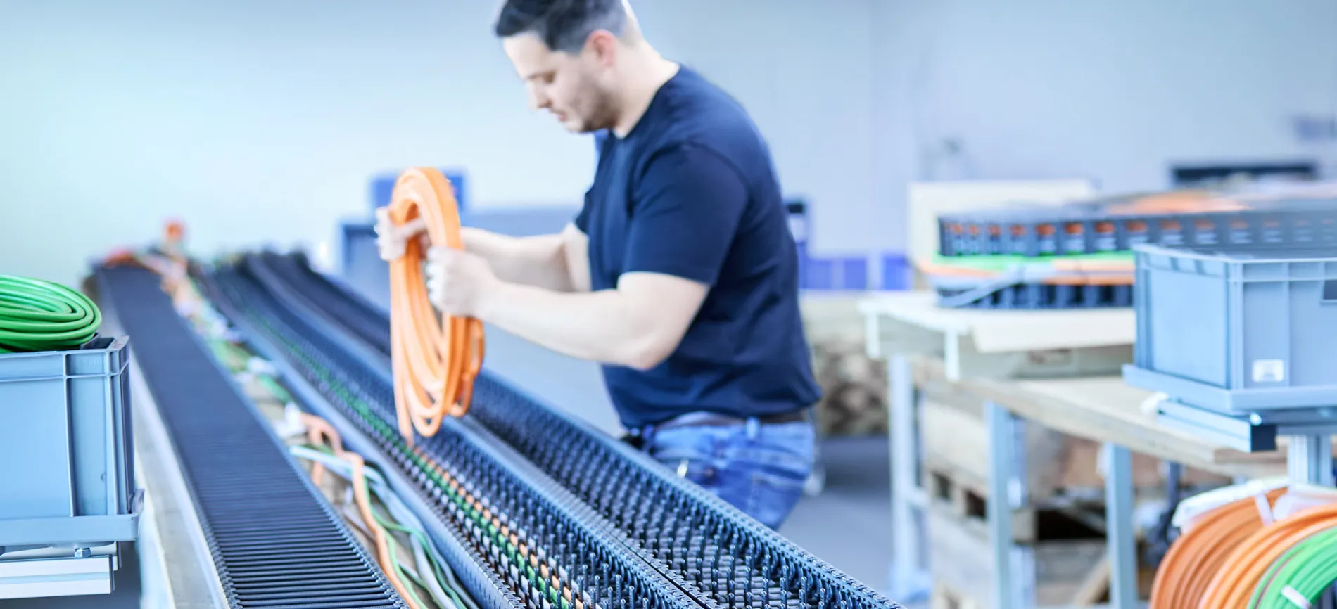 Du siehst einen Mitarbeiter bei HELU KABEL, der in der Fertigung Kabel vorbereitet und sortiert.