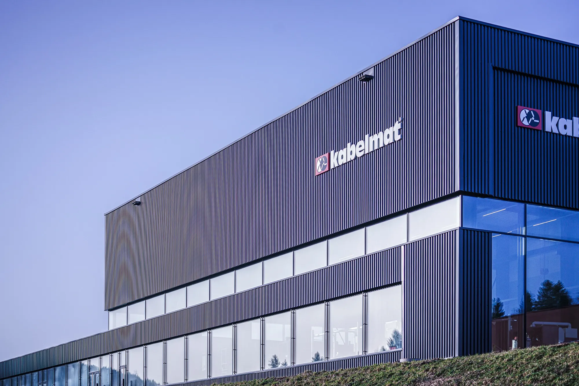 Industriegebäude von HELU KABEL GmbH mit "kabelmat" Logo, modernes Design unter klarem Himmel.