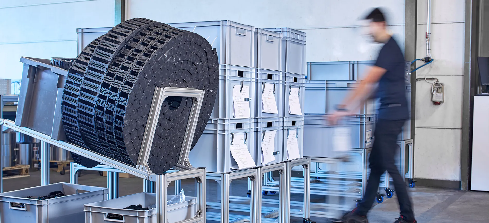 Du siehst einen Mitarbeiter in der Produktion, der Materialkisten bei HELU KABEL im Lager bewegt.