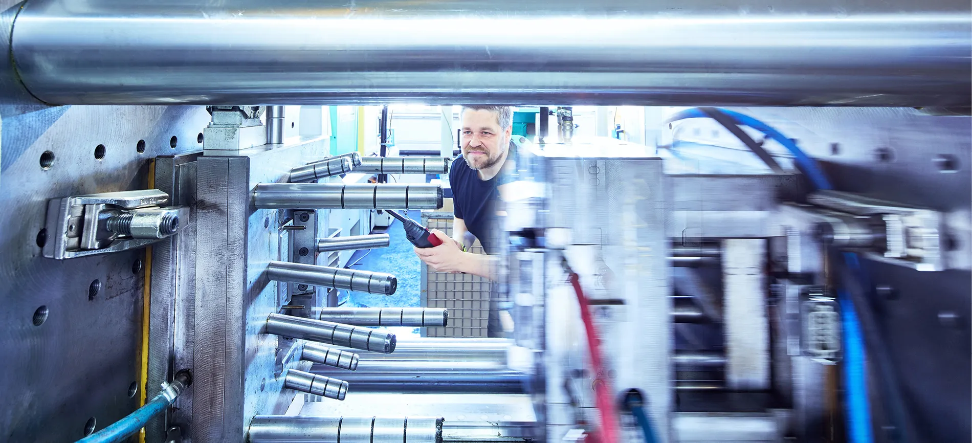 Ein Produktionsmitarbeiter arbeitet mit einer Industriemaschine in der Fertigungshalle.