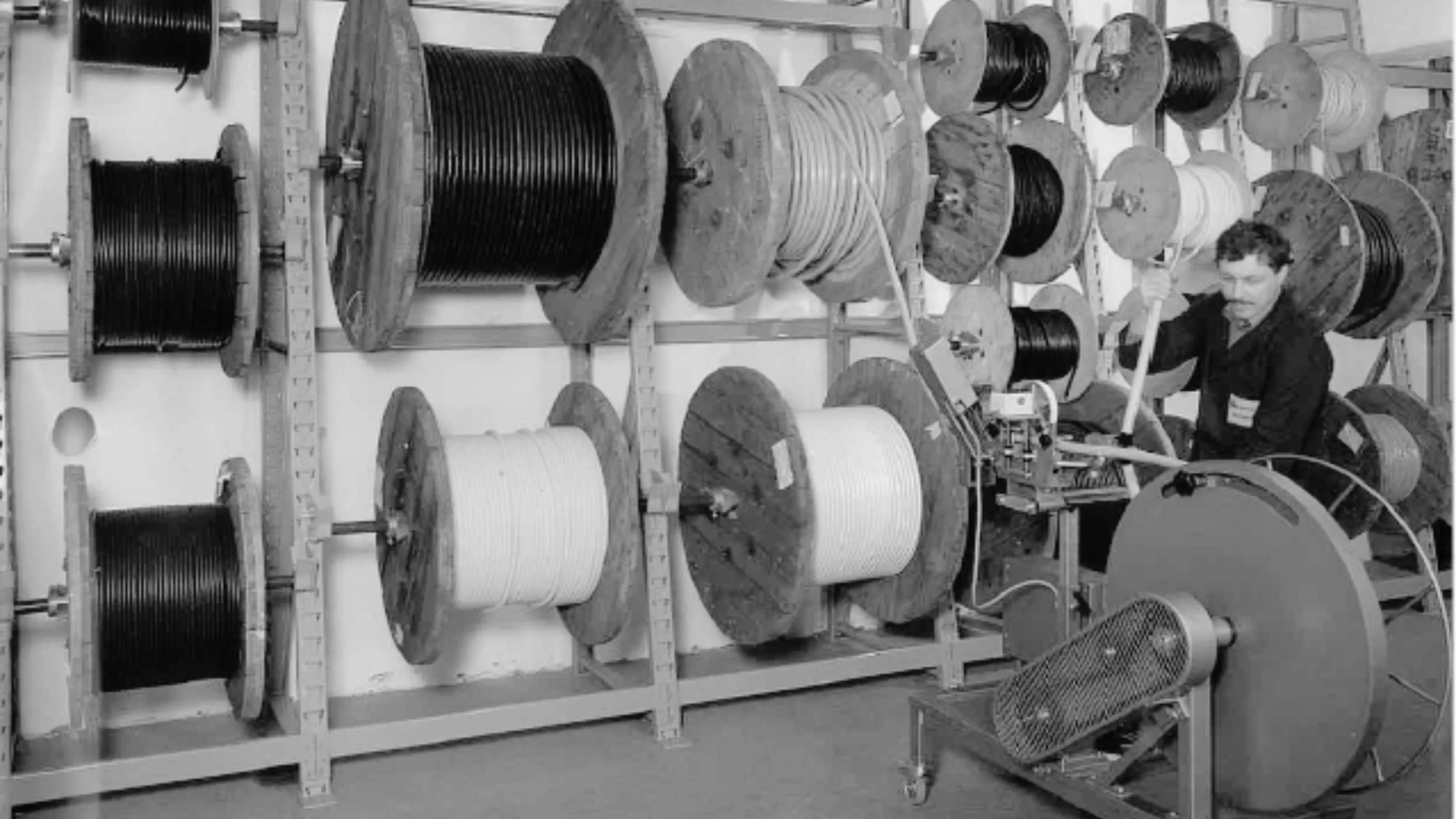 Ein Mitarbeiter von HELU KABEL bedient eine Maschine, um Kabel von großen Rollen abzuwickeln.