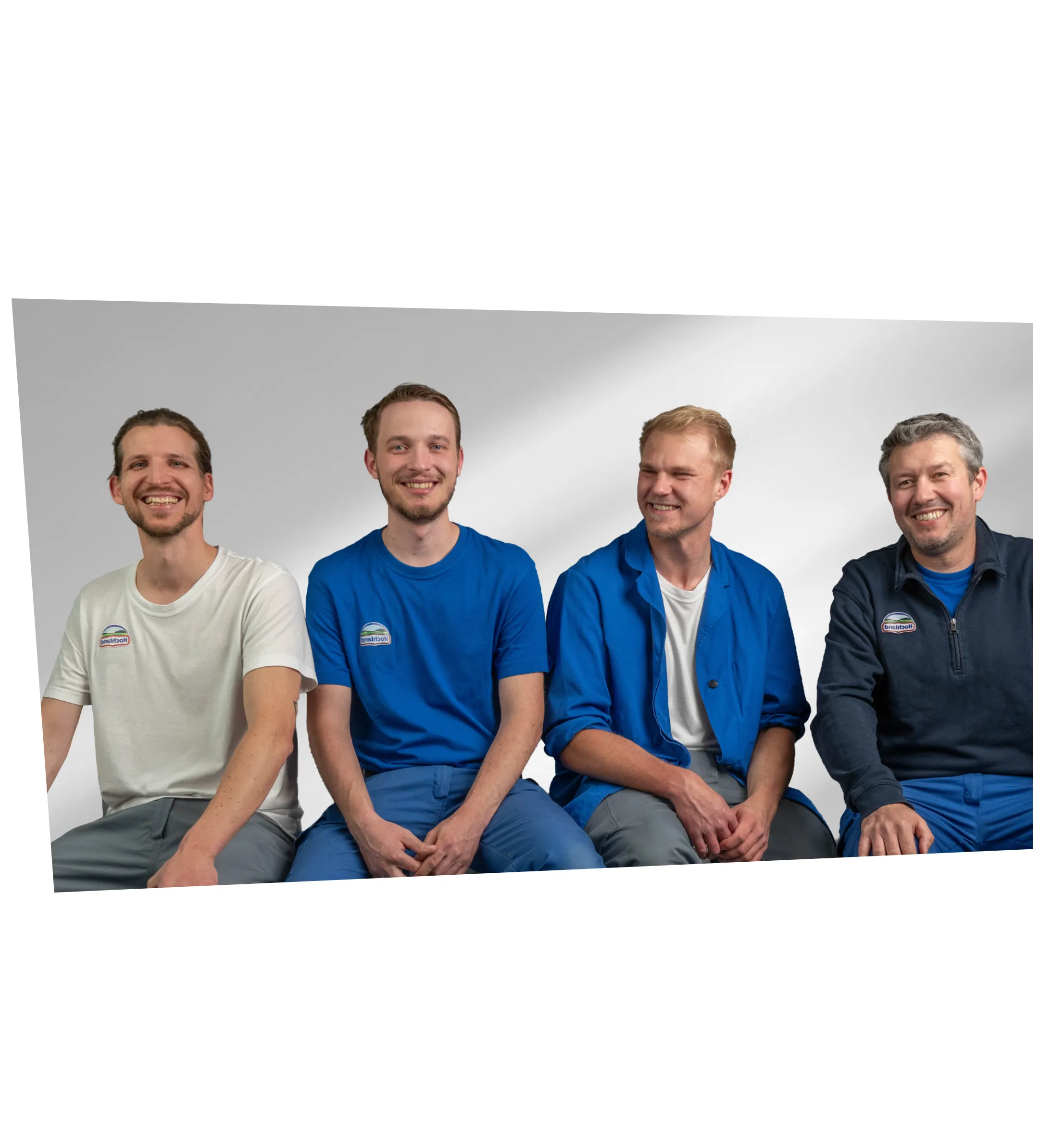 Vier freundliche Kollegen aus der Lebensmittelbranche sitzen gemeinsam und lächeln in die Kamera.