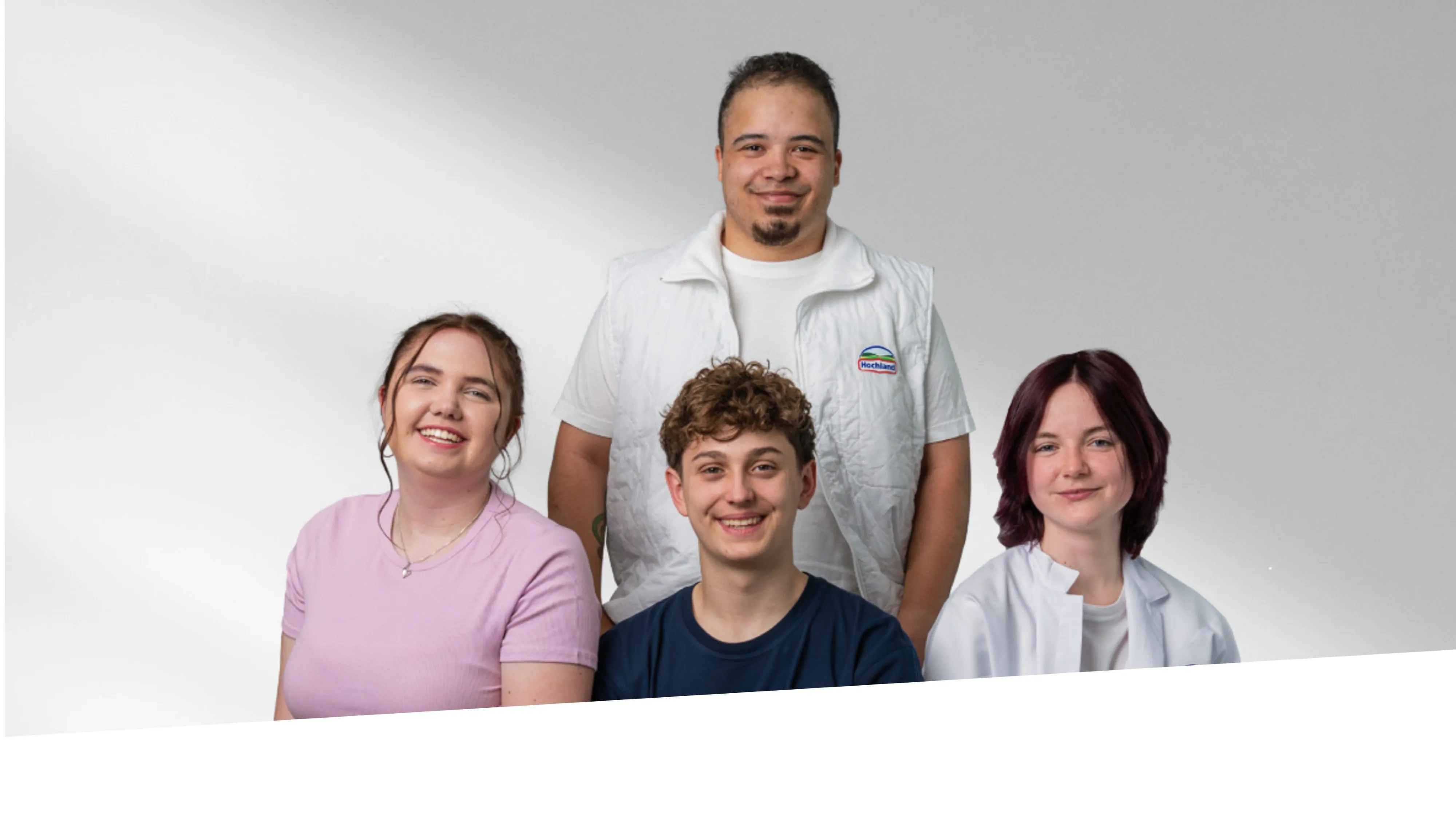 Vier junge Menschen, freundlich lächelnd, präsentieren sich als Team bei Hochland im Bereich Lebensmittel.