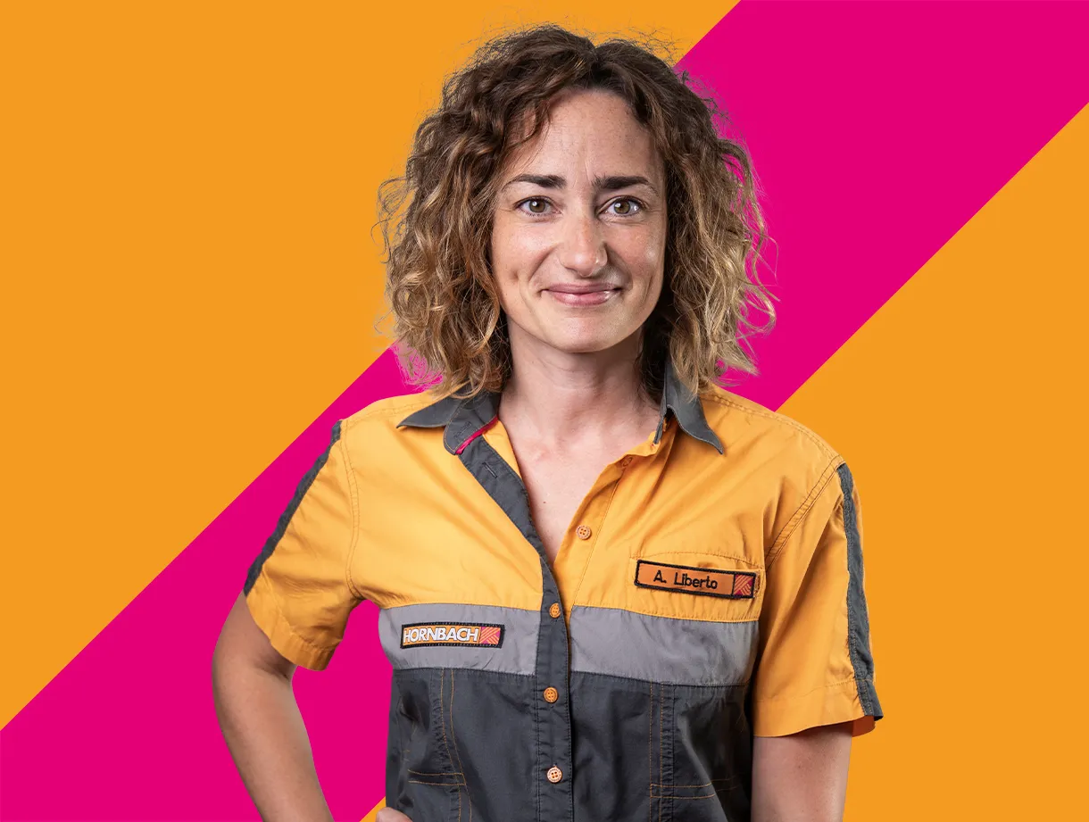 Ein Mitarbeiter von HORNBACH in orange-grauer Arbeitskleidung vor einem farbenfrohen Hintergrund.