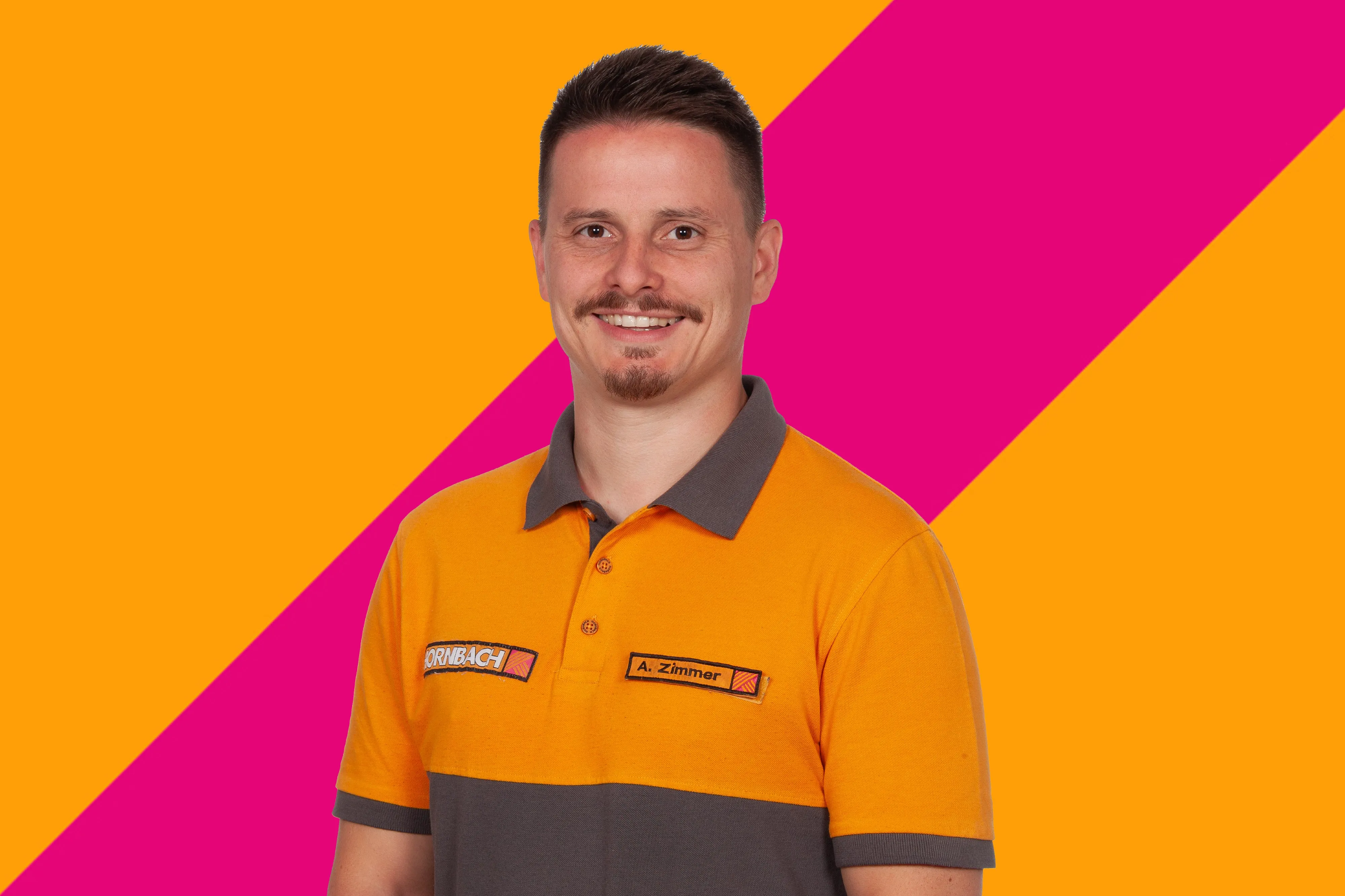 L'employé Andreas Zimmer de HORNBACH souriant, portant un polo orange et gris, sur fond coloré.